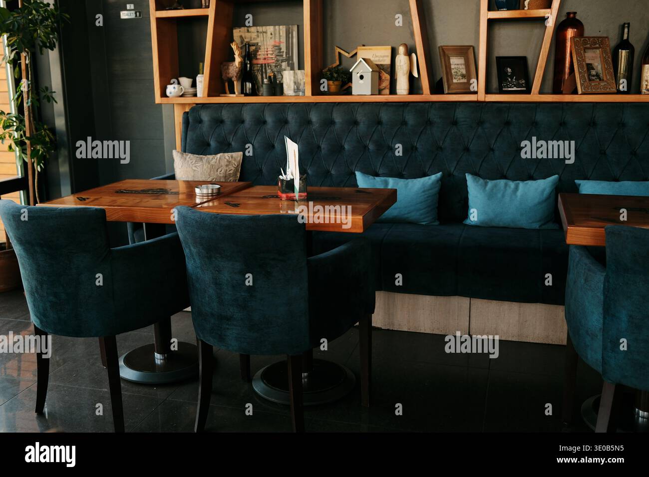 Intérieur de café moderne et confortable avec des sièges rembourrés, des tables en bois et des étagères décoratives créant une atmosphère agréable pour les repas. Bijeljina, Bosnie Banque D'Images