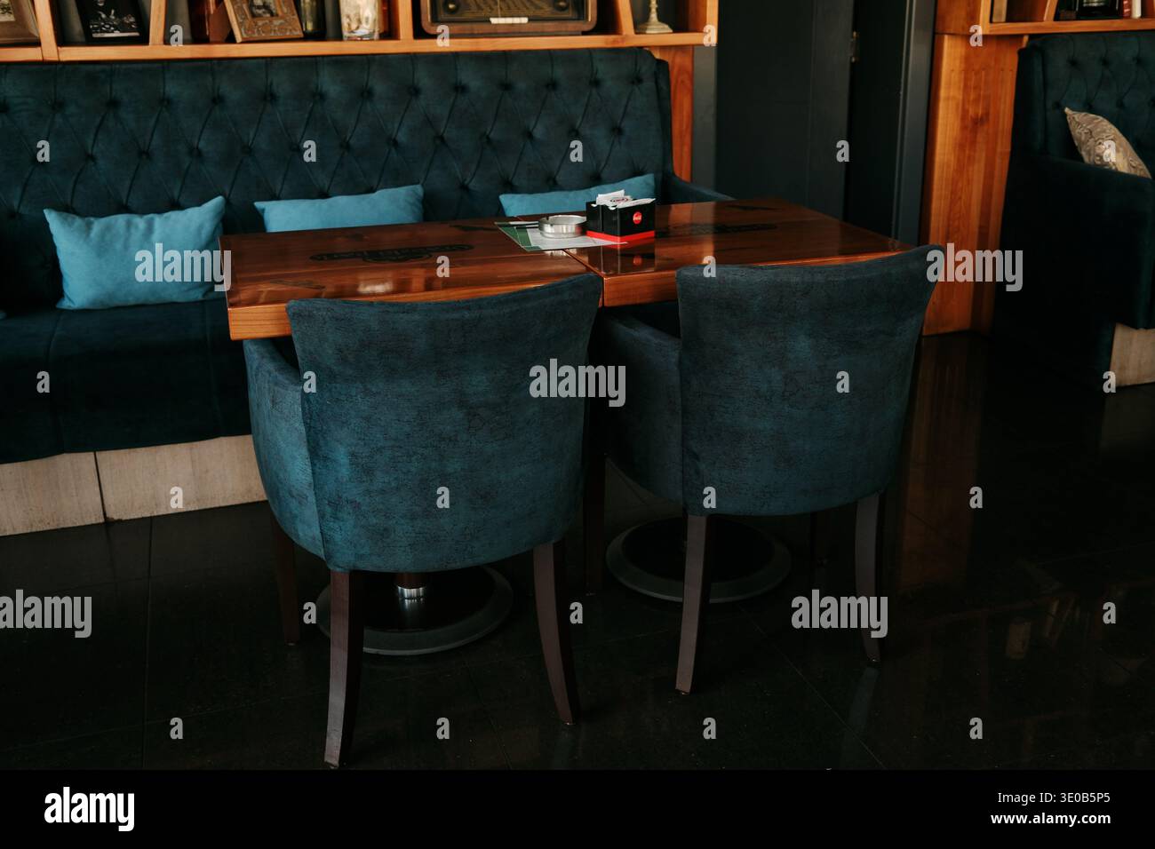 Intérieur de café moderne et confortable avec des sièges rembourrés, des tables en bois et des étagères décoratives créant une atmosphère agréable pour les repas. Bijeljina, Bosnie Banque D'Images