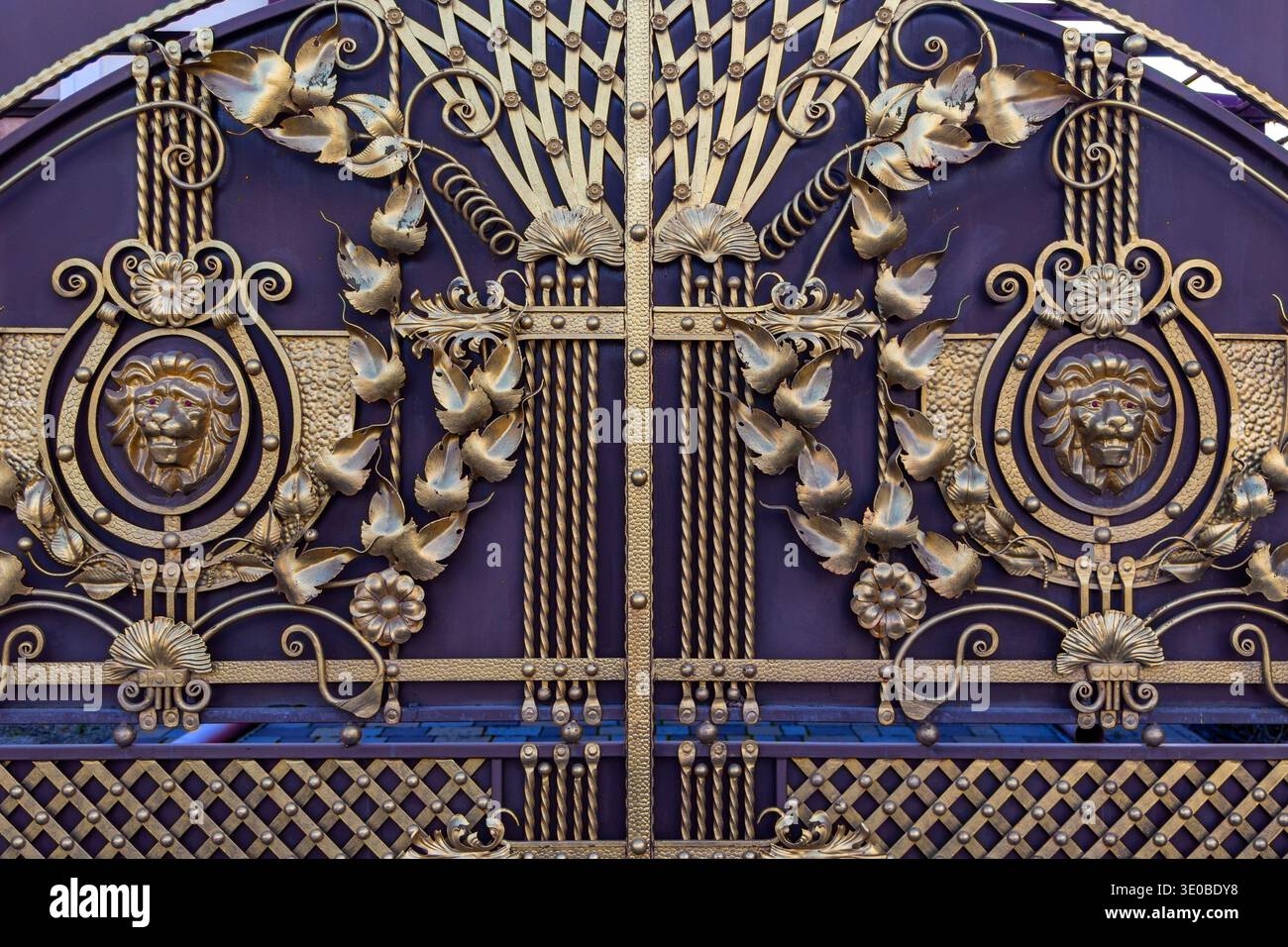 Portail en fer forgé orné de motifs lion. Gros plan détaillé d'une porte décorative en métal présentant des têtes de lion, des éléments floraux et des volutes élégantes Banque D'Images