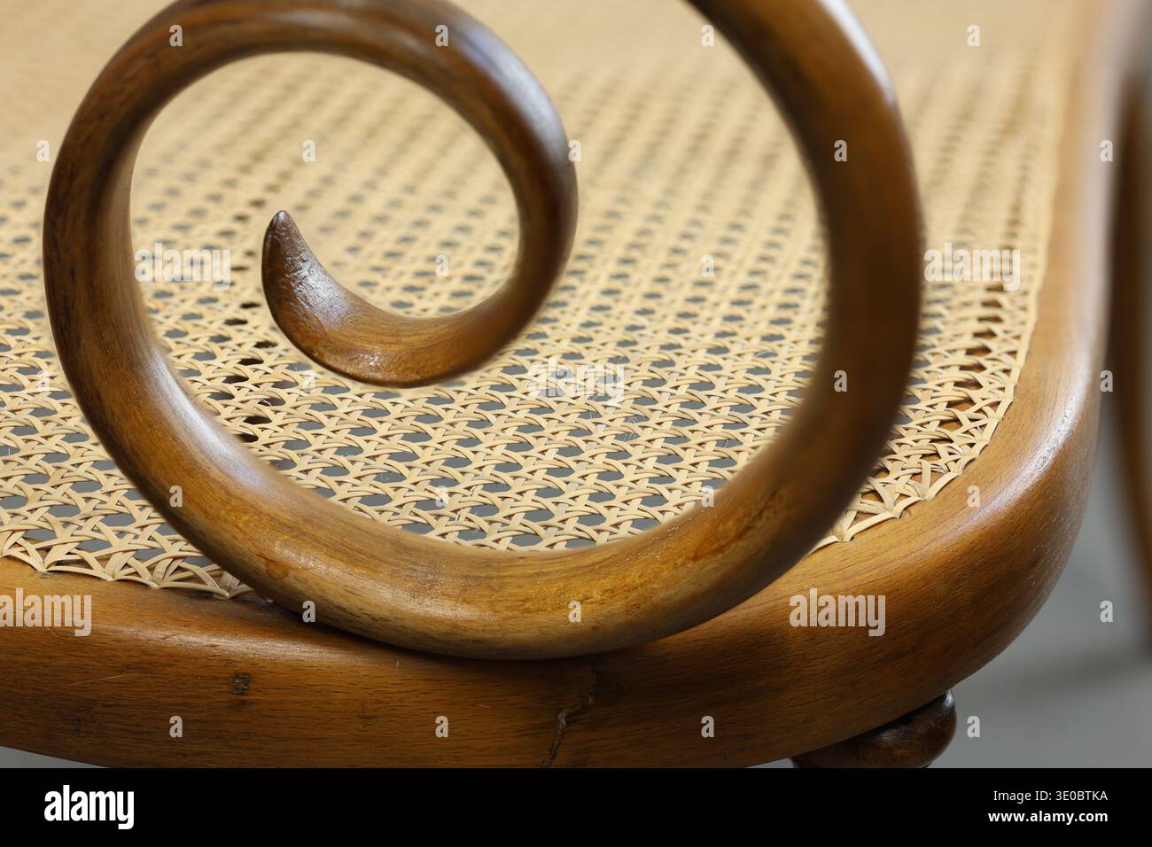 Une vue rapprochée d'une chaise en bois avec un motif en spirale sur l'accoudoir et une cannelure tissée. Le savoir-faire met en valeur l'élégance et la tradition en furni Banque D'Images