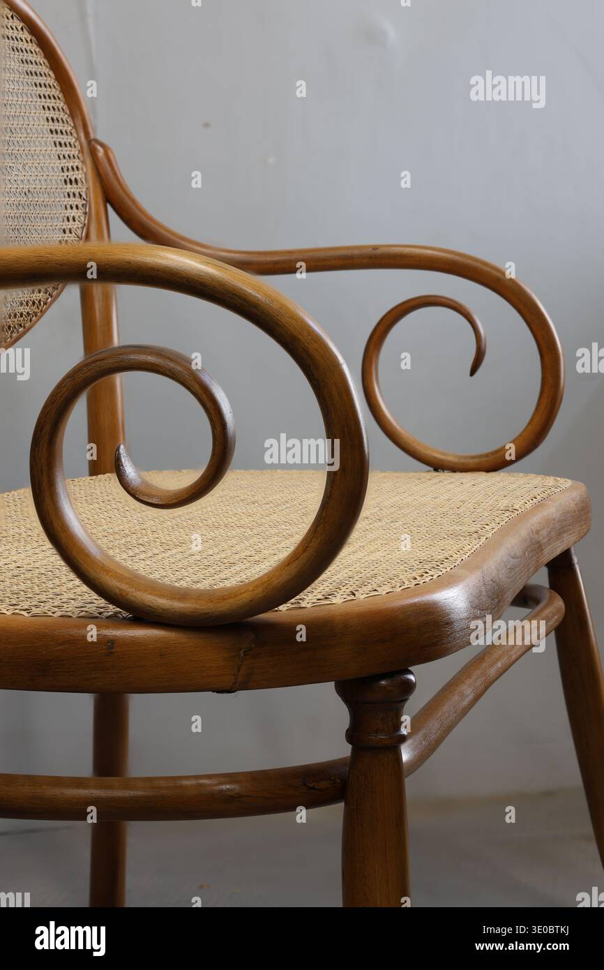 Une vue détaillée d'une chaise en bois avec un accoudoir magnifiquement incurvé. La chaise présente des matériaux naturels avec des sièges tissés. Parfait pour ajouter Banque D'Images