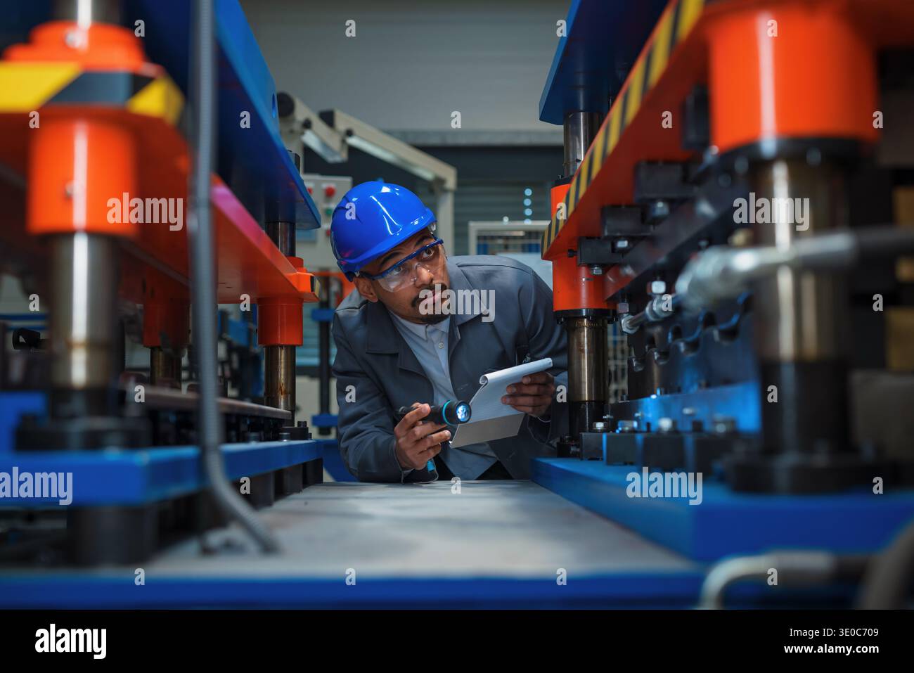 Un ingénieur afro-américain vérifie les machines et les équipements dans une usine pour le contrôle de la qualité et la maintenance. Il suit les protocoles de sécurité. Banque D'Images
