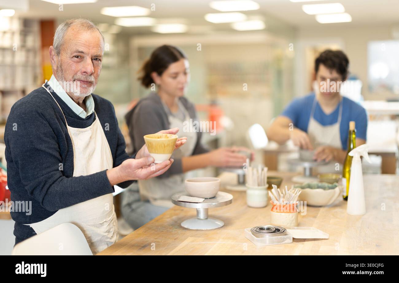 Le potier mûr démontre une coupe d'argile qu'il a faite de ses propres mains Banque D'Images