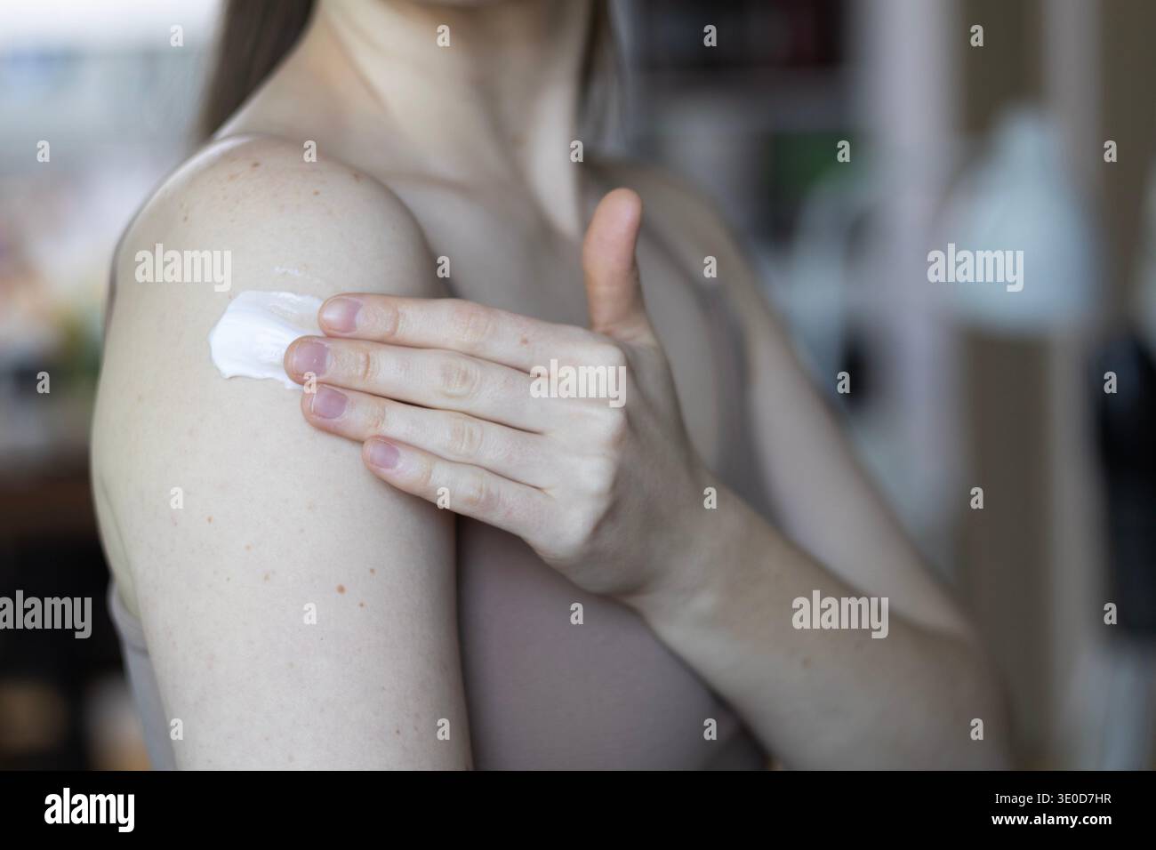 Séoul, Corée du Sud - 03.12.2026 : gros plan d'une jeune femme appliquant une crème hydratante sur son épaule. Concept de soin de la peau, routine de soin du corps Banque D'Images