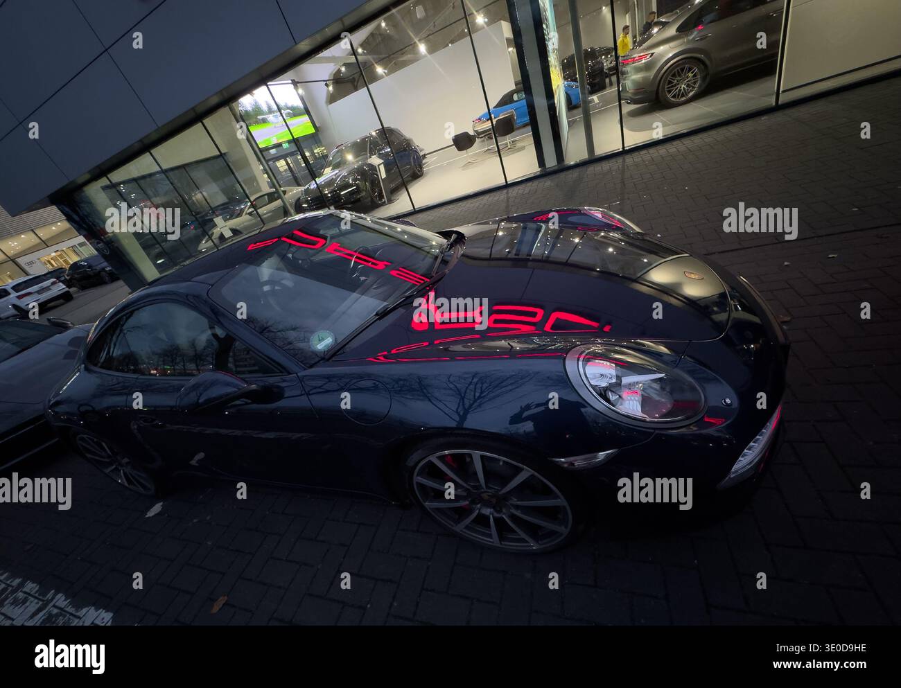 13.11.2025, Allemagne, Brême, Brême - reflet du logo Porsche illuminé sur une nouvelle Porsche, devant le concessionnaire Porsche agréé Porsche cent Banque D'Images