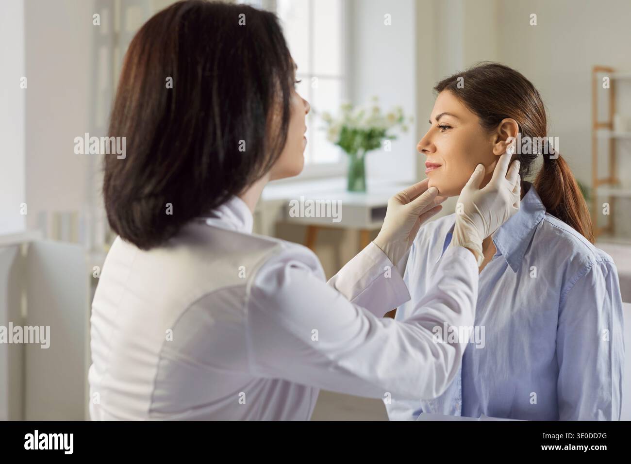 Dermatologue vérifiant le visage de la patiente lors d'une consultation de soins en clinique Banque D'Images