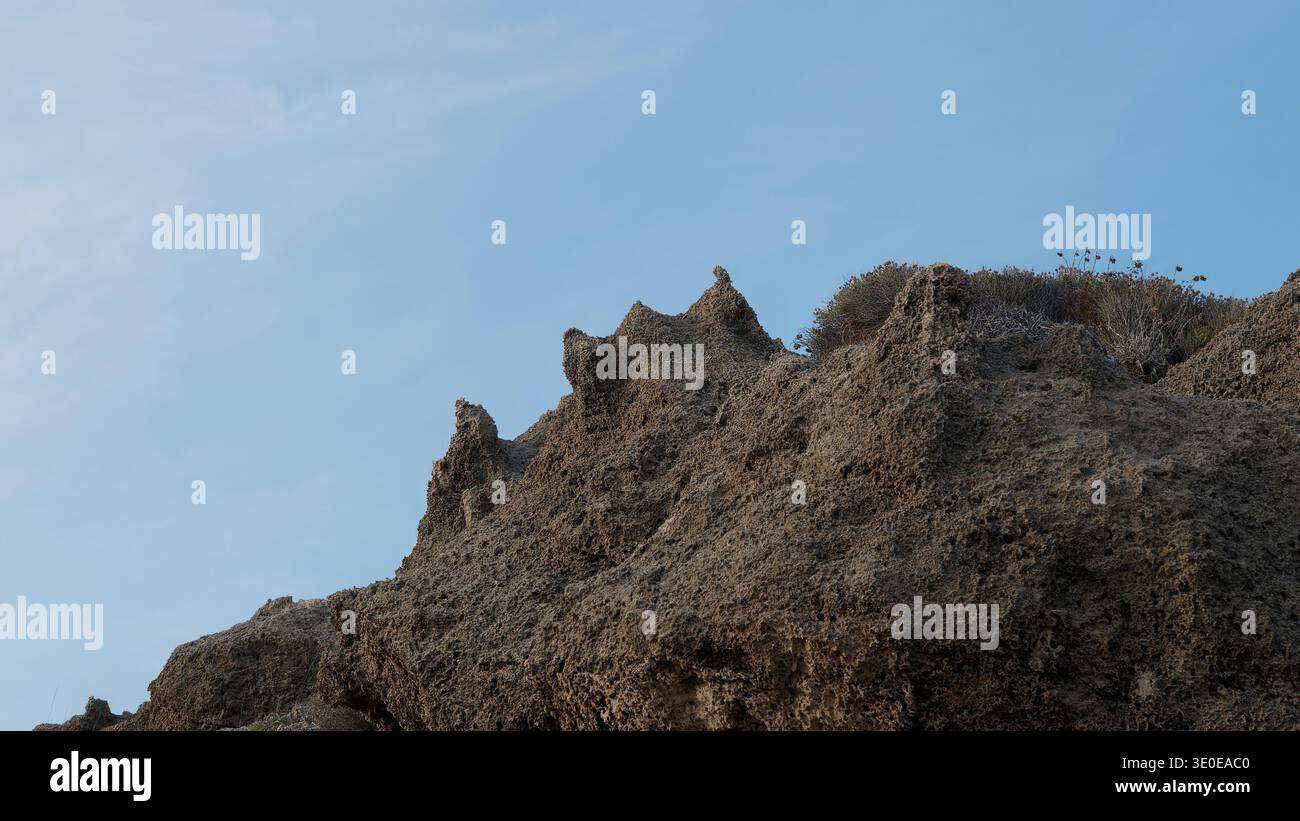 Falaise rocheuse érodée spectaculaire avec des pics dentelés contre Clear Blue Sky Banque D'Images