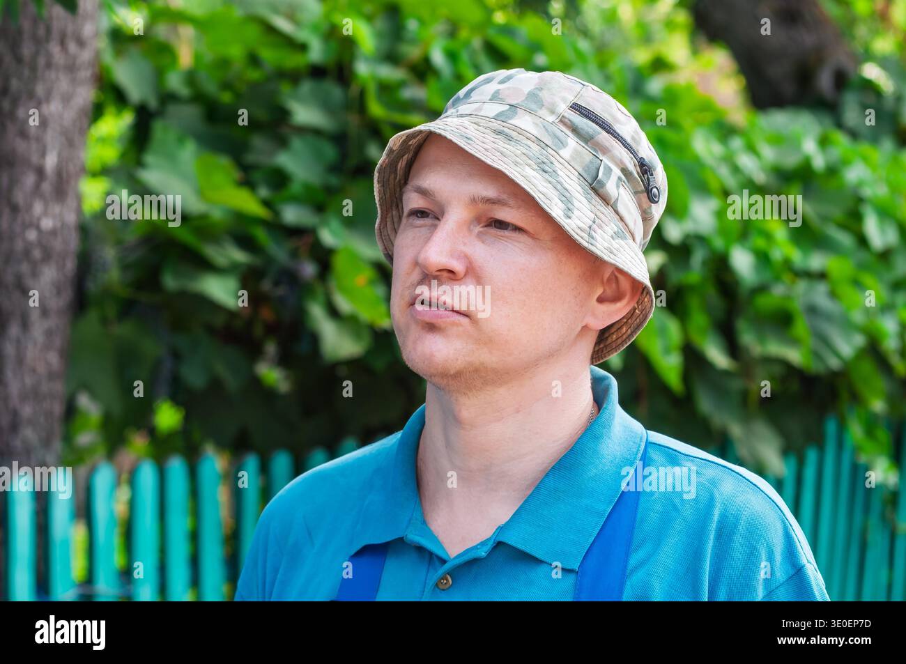 Homme dans le chapeau seau camouflage regardant sur le côté par une journée ensoleillée Banque D'Images