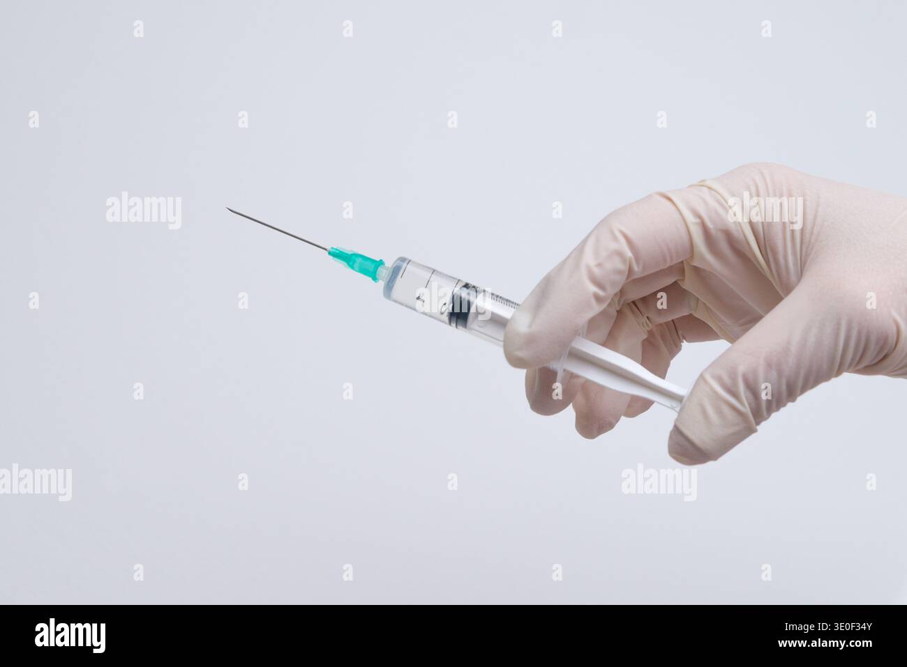 Main gantée tenant la seringue prête pour l'injection, la vaccination de soins de santé et le concept de procédure médicale Banque D'Images
