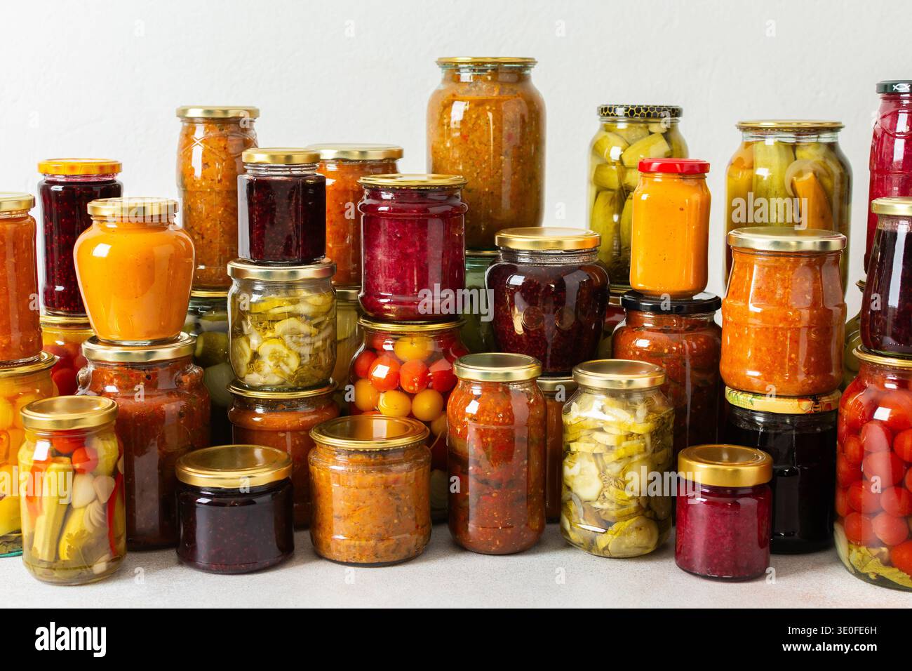 Les légumes et les fruits en conserve sont empilés sur une étagère, préparés pour une utilisation hivernale. Divers pots contiennent différentes conserves, mettant en valeur les efforts minutieux pour stocker les aliments pendant la saison Banque D'Images
