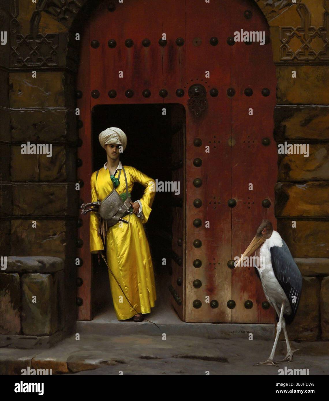 Le Marabou (1888) 'huile sur toile, 39 X 30,5 cm' [Arnot Art Museum, Elmira, New York] -- Jean-Léon Gérôme (1824 - 1904) dans cette œuvre, un homme arabe s'appuie contre un montant de porte tandis qu'un marabou marche dans la rue. Certains chercheurs suggèrent que le fouet que l'homme tient indique que le marabou est son animal de compagnie. Le détail précis des textures – maçonnerie grossièrement taillée, décoration finement sculptée, grain de bois de la porte, richesse de la robe de satin de l’homme, plumage mou de l’oiseau – est caractéristique du style de Gérôme et témoigne de ses compétences techniques. Les intérêts ornithologiques de Gérôme sont w Banque D'Images