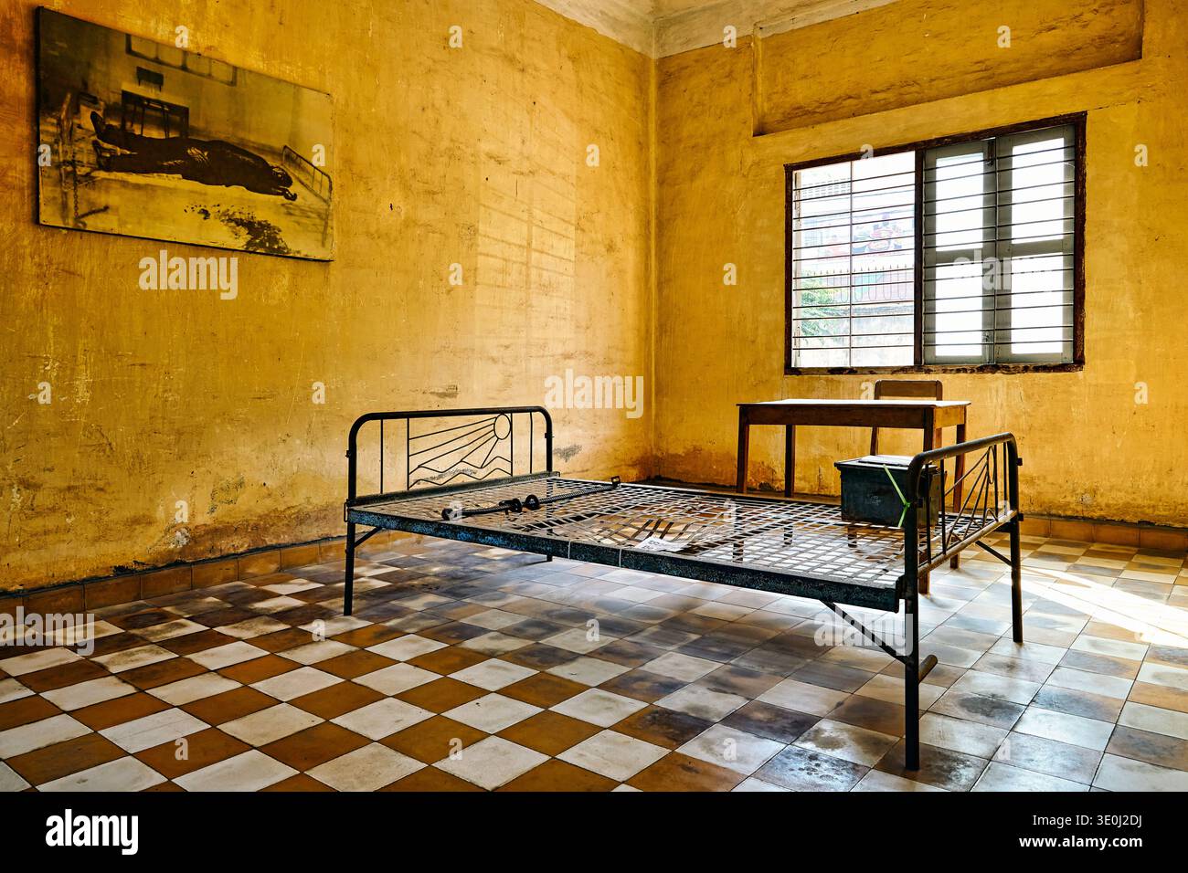 Voici une cellule du Musée du génocide Tuol Sleng à Phnom Penh. Il a un lit avec des chaînes et une photo d'une victime sur le mur. Banque D'Images