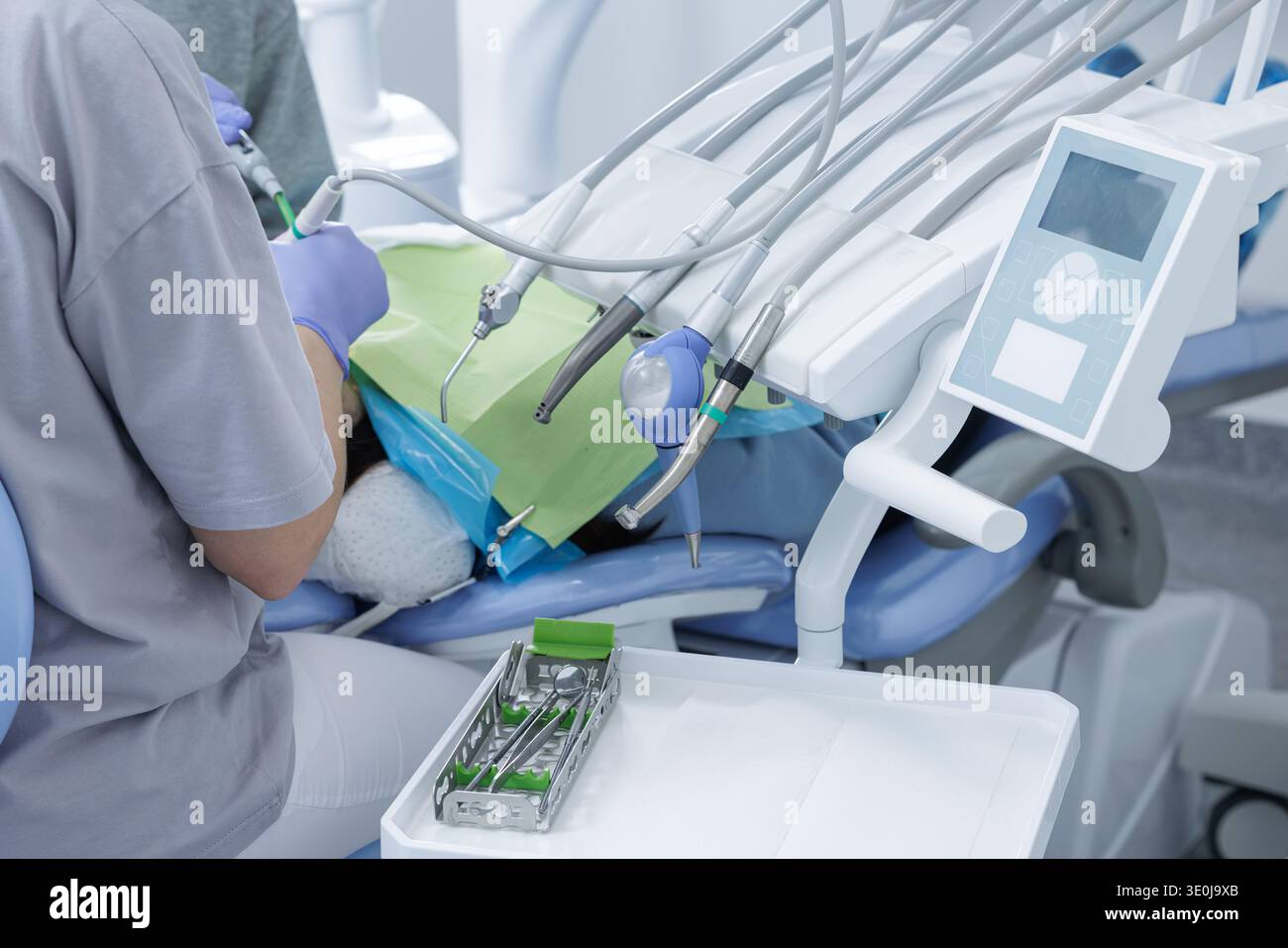 Vue large du dentiste travaillant sur le patient dans la clinique dentaire moderne avec chaise, instruments et panneau de commande. Environnement dentaire contemporain avec pro Banque D'Images