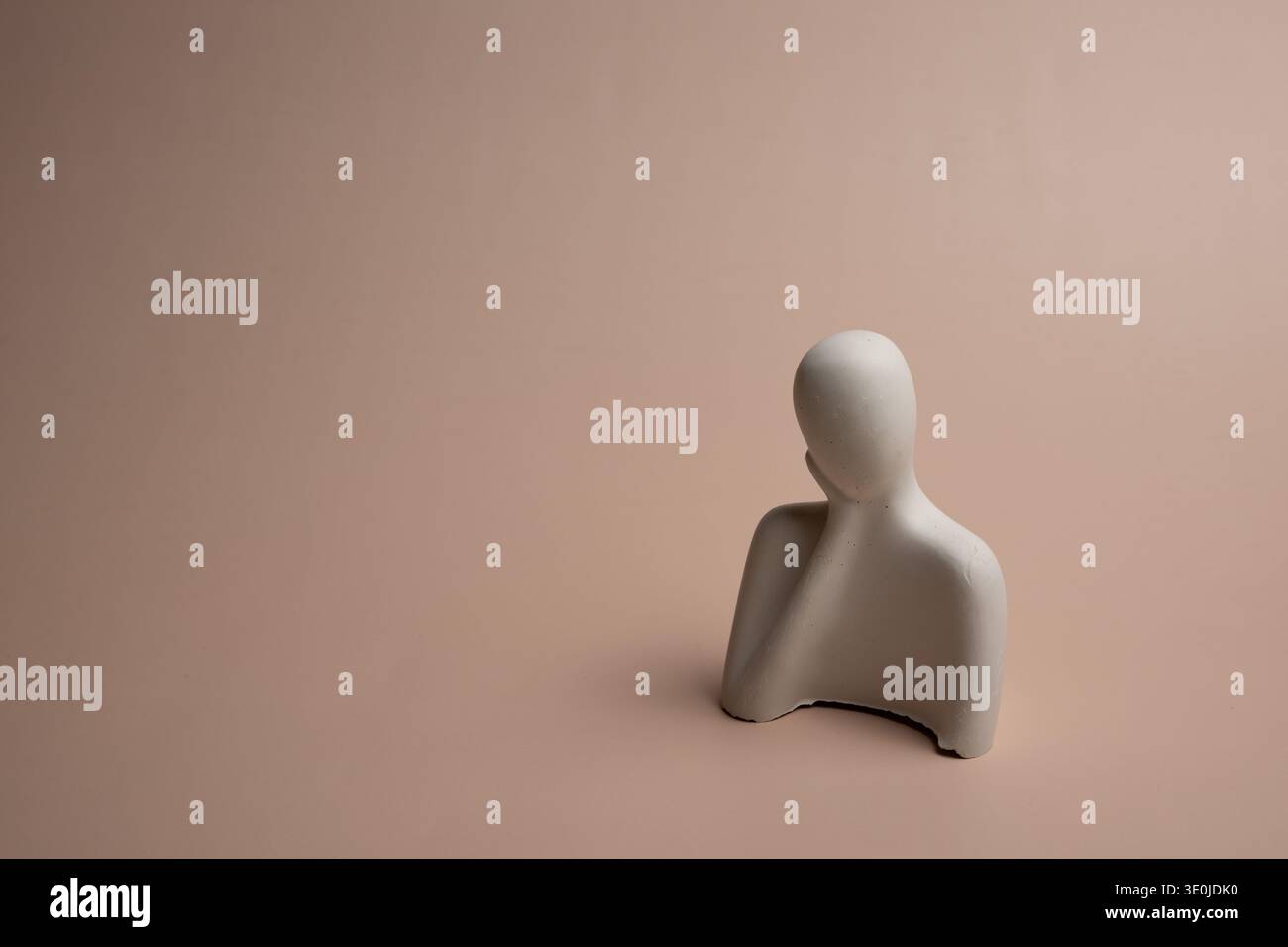 Une seule figure en céramique blanche placée sur un fond beige avec un grand espace de copie symbolise l'individualité, l'unicité et se démarquer au sein de la société Banque D'Images