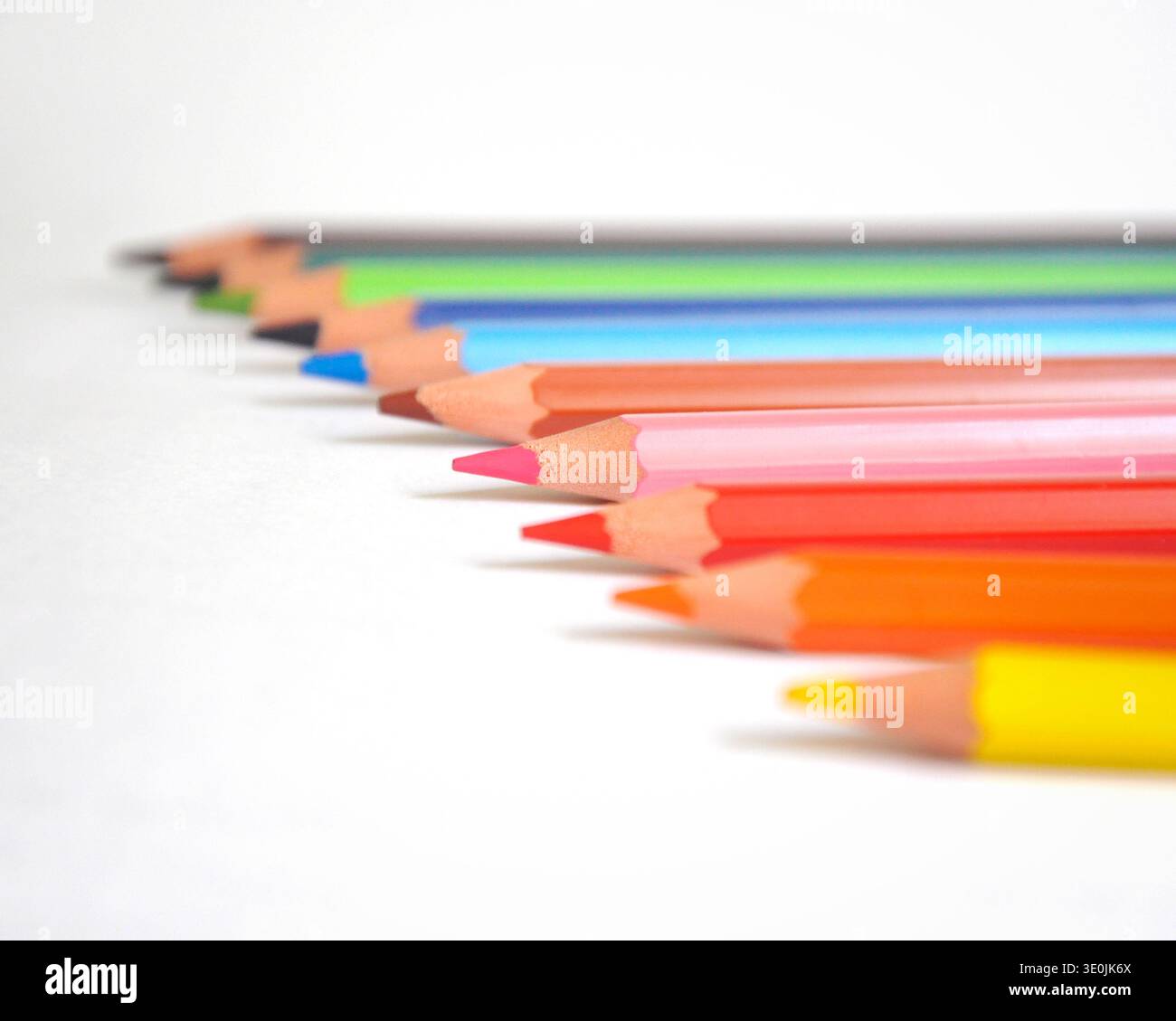 Gros plan de crayons de couleur colorés sur un fond blanc propre. L'image met en évidence des couleurs éclatantes, des pointes de crayon nettes et une faible profondeur de champ. Banque D'Images