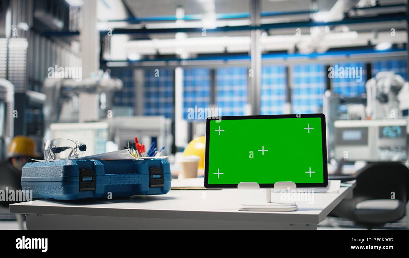 Bureau et espace de travail vides avec lunettes de sécurité et écran PC dans une installation à énergie solaire, où les bras robotisés rationalisent le processus d'assemblage des panneaux photovoltaïques. Indicateurs de performances. Banque D'Images
