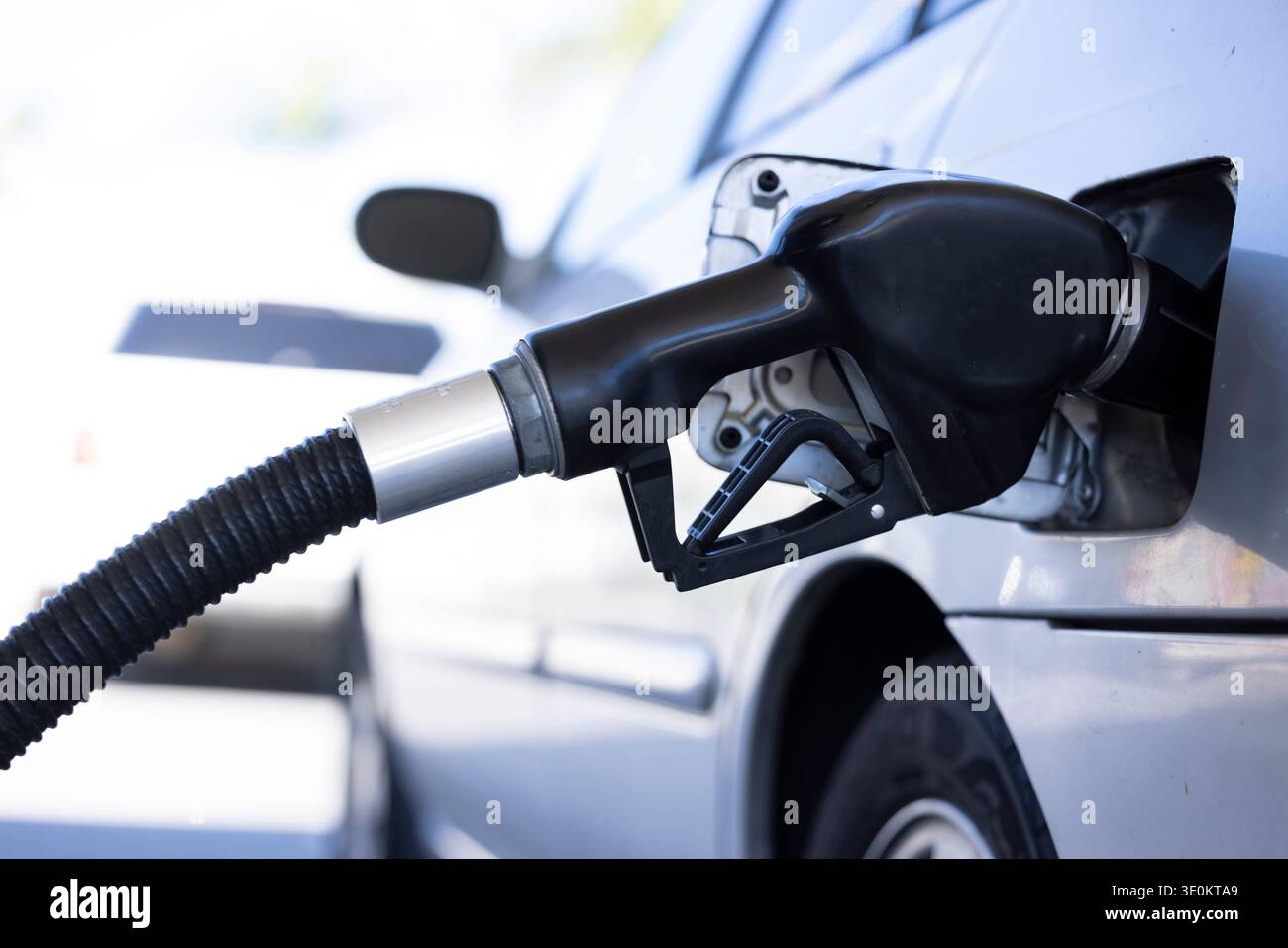 Un tuyau de pompe à essence remplit le réservoir d'essence d'une voiture à une station-service. Banque D'Images