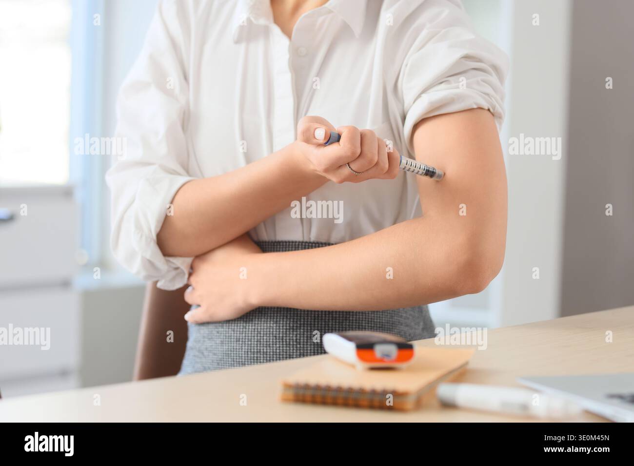Jeune femme d'affaires enceinte avec diabète gestationnel utilisant un stylo lancette à table dans le bureau, gros plan Banque D'Images