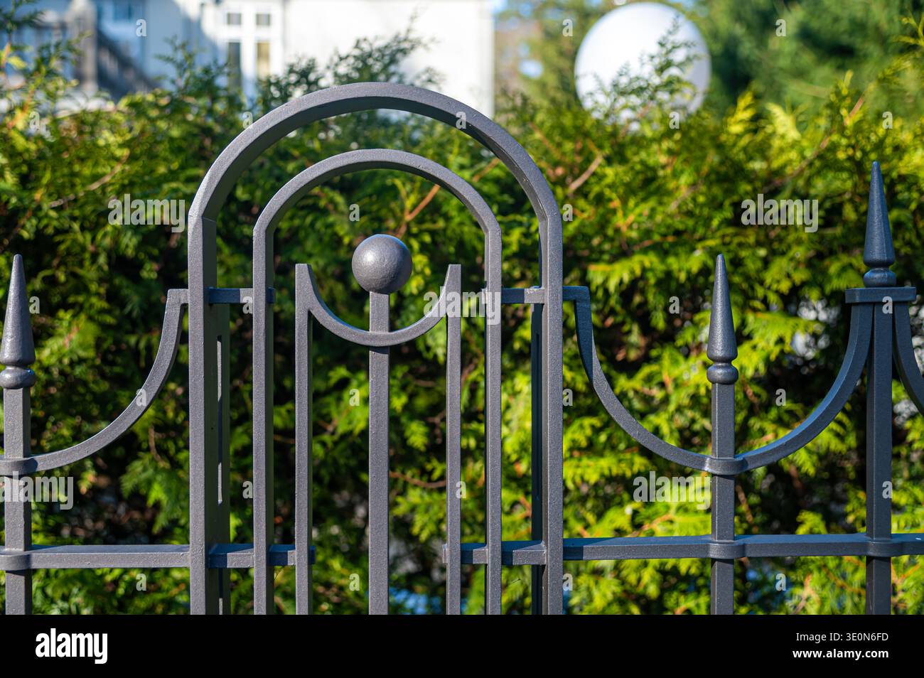 Une vue rapprochée d'une porte métallique montrant les détails devant des plantes vertes et des bâtiments. Banque D'Images