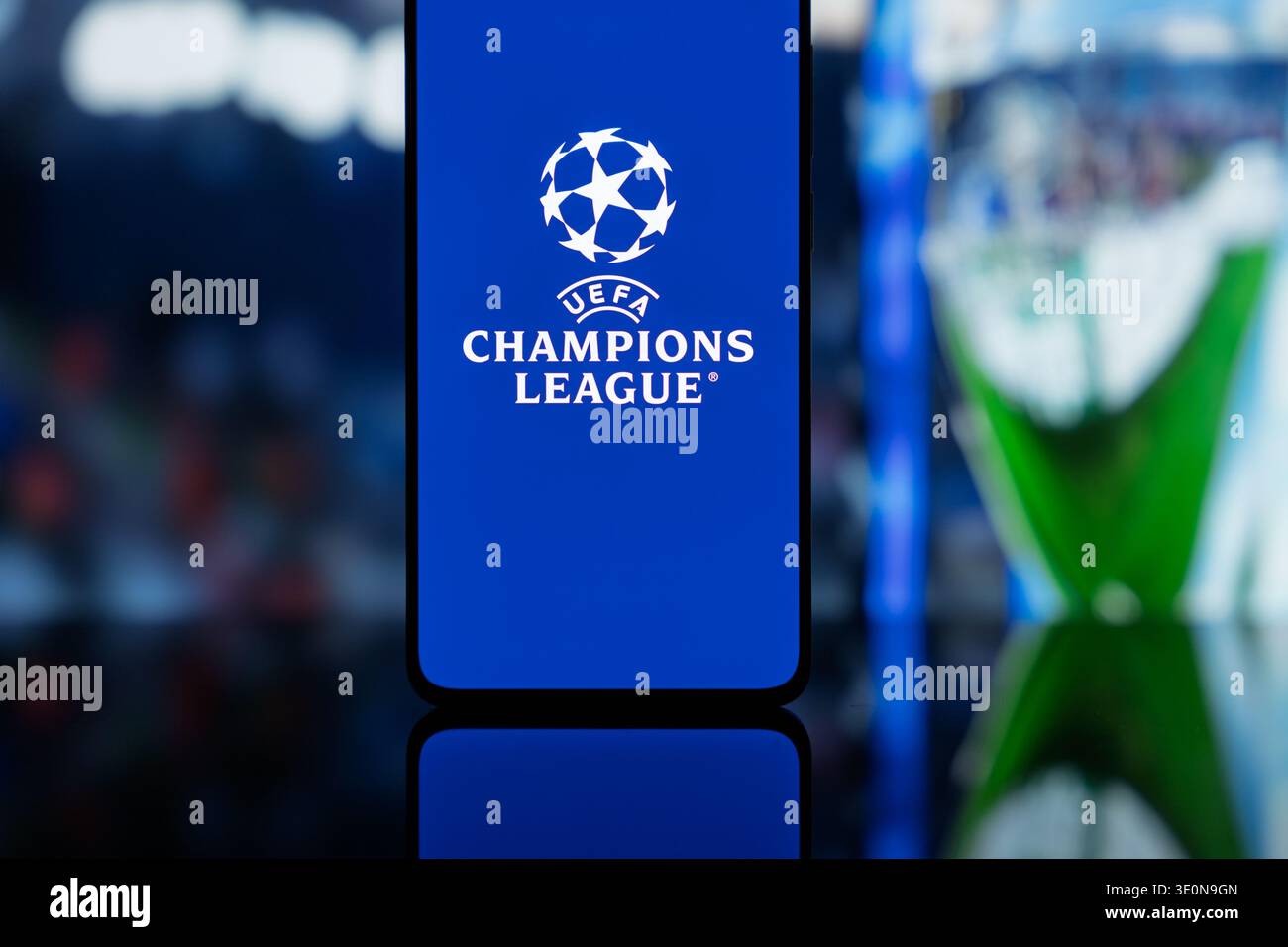 Smartphone affichant le logo officiel de l'UEFA Champions League sur un écran bleu, avec un fond flou du stade de football, représentant le numérique Banque D'Images