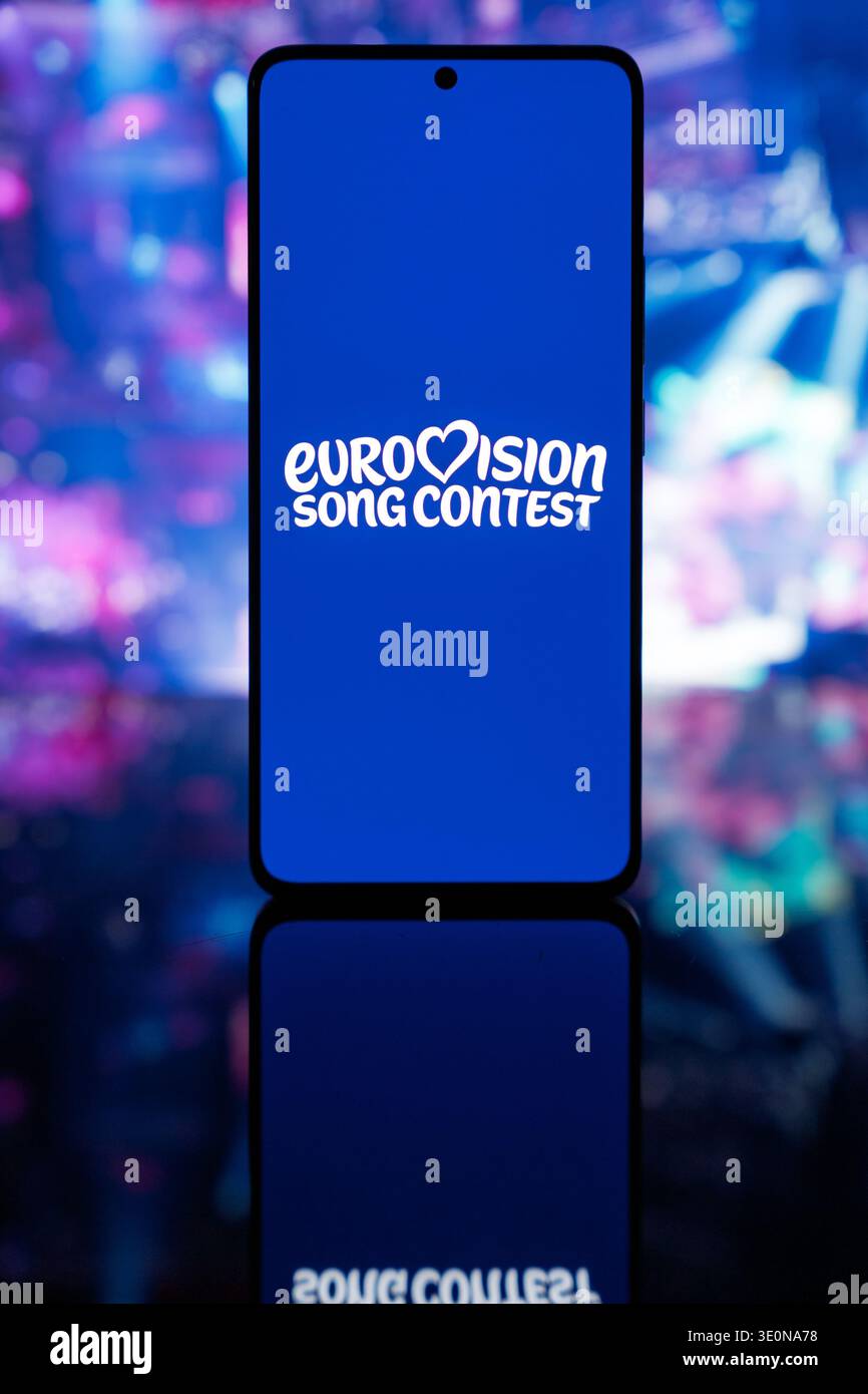 Logo officiel du concours Eurovision de la chanson sur un écran bleu, avec une scène colorée floue et un fond lumineux, représentant la musique internationale Banque D'Images