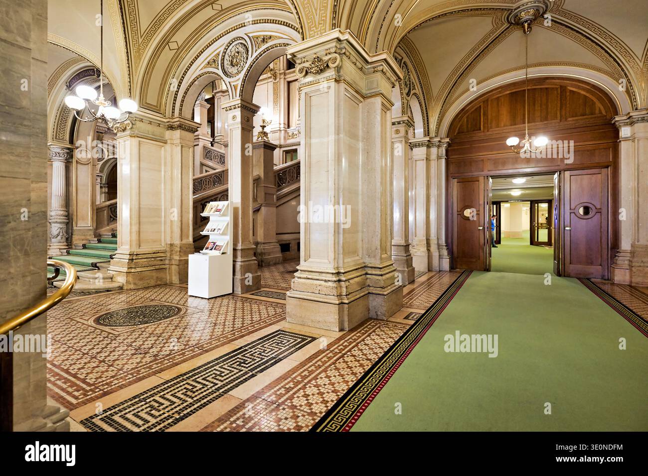Les visiteurs explorent l'Opéra national de Vienne avec son grand escalier, ses arches et ses planchers à motifs présentant des éléments de design historiques. Banque D'Images
