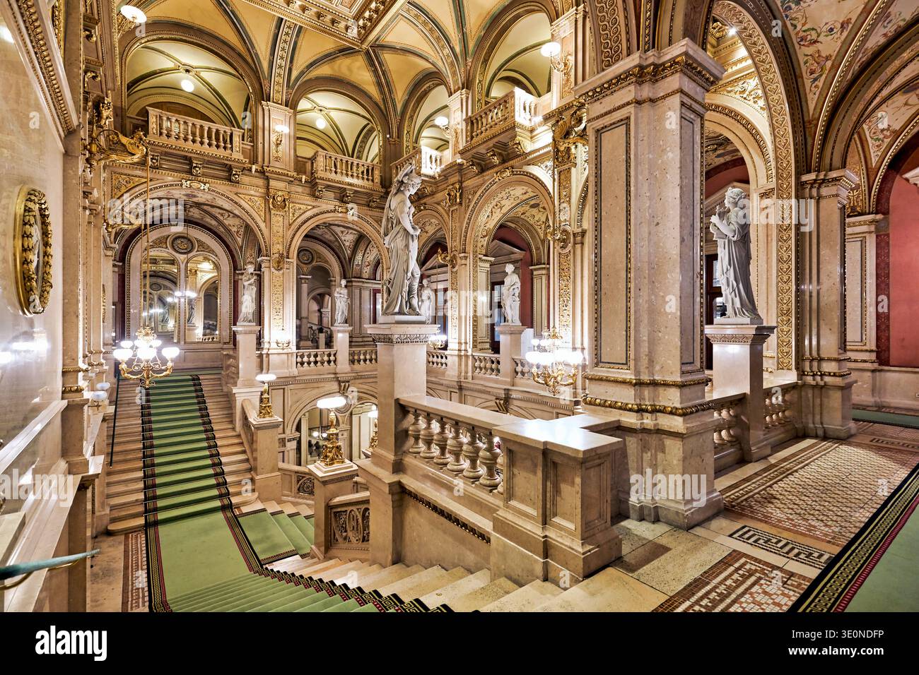 Les visiteurs peuvent admirer le grand escalier et le hall de l'Opéra national de Vienne. La zone présente des statues et des lumières décoratives lumineuses. Banque D'Images