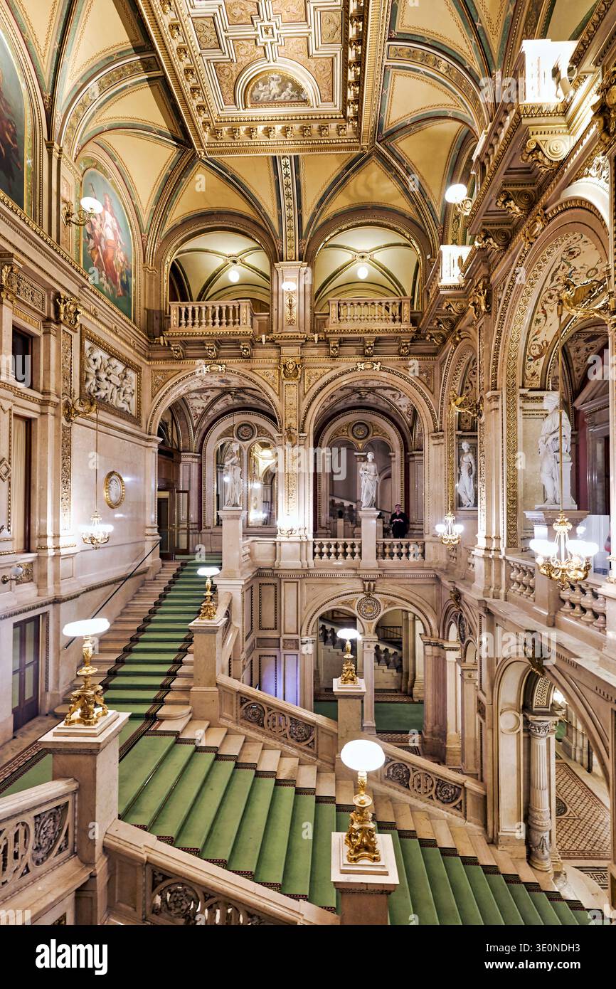 Les visiteurs admirent le grand escalier et l'architecture détaillée de l'Opéra national de Vienne, mettant en valeur sa riche histoire et son importance culturelle. Banque D'Images