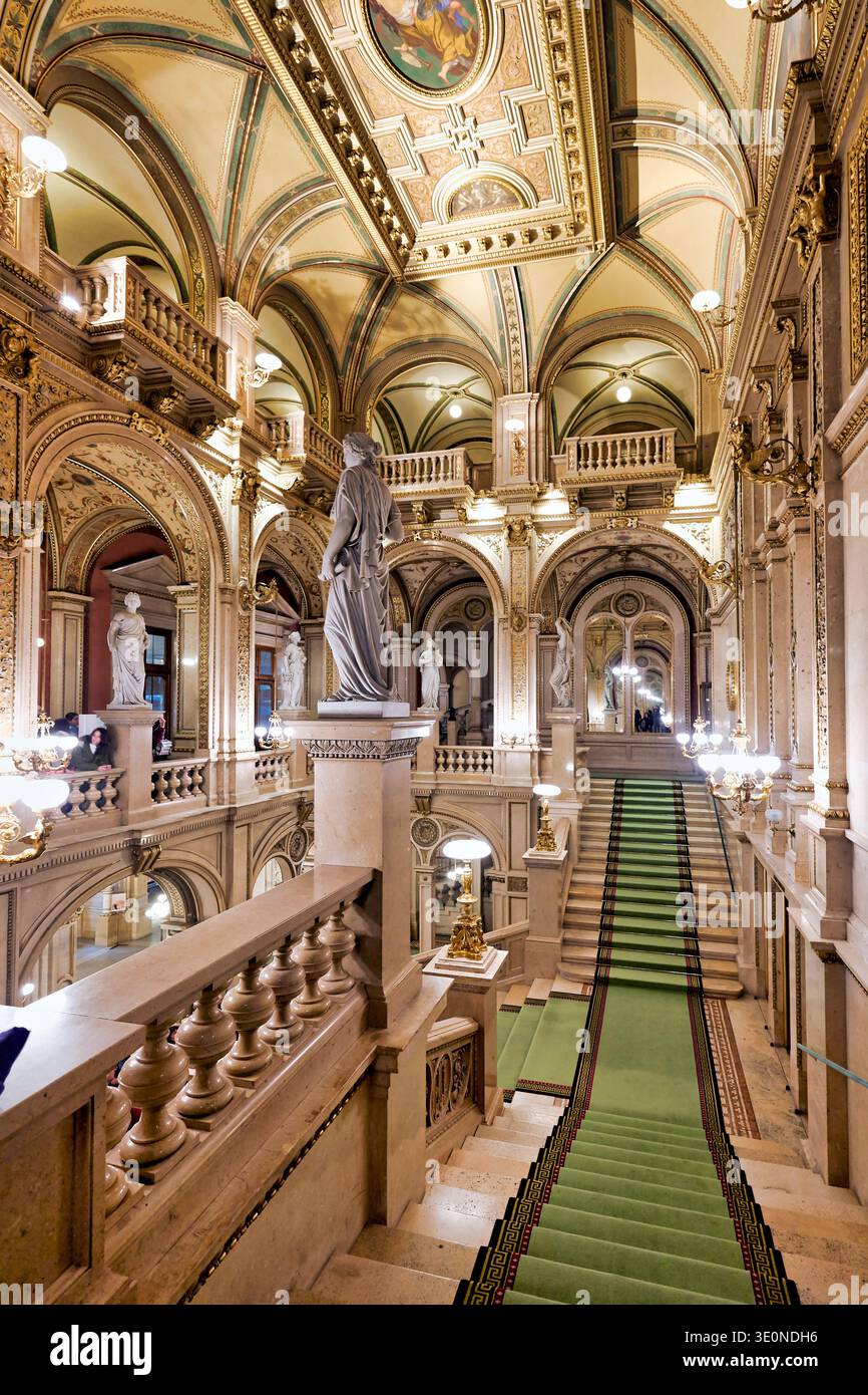Les gens apprécient l'intérieur historique de l'Opéra national de Vienne. Le grand escalier et les statues attirent l'attention de la foule. Banque D'Images