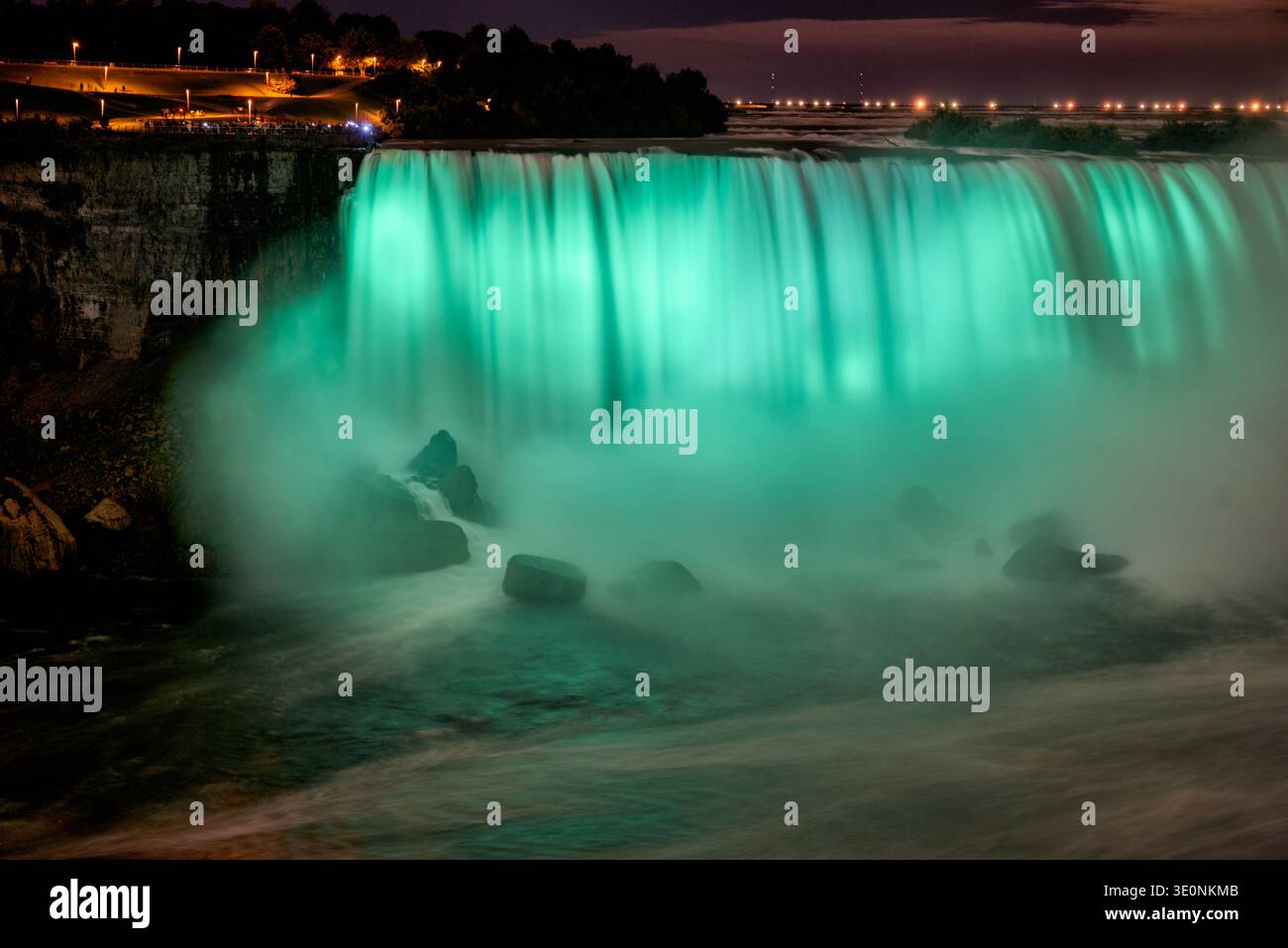 Les touristes se rassemblent aux chutes du Niagara, au Canada, pour assister aux majestueuses chutes en fer à cheval illuminées dans un vert vif la nuit, créant un spectacle époustouflant Banque D'Images