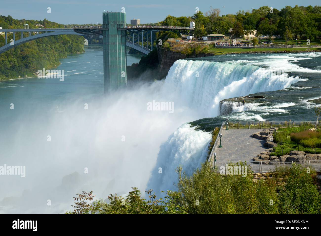 Les touristes voient les puissantes chutes du Niagara du côté américain, avec le pont Rainbow et la tour d'observation en arrière-plan, profitant de la nature Banque D'Images