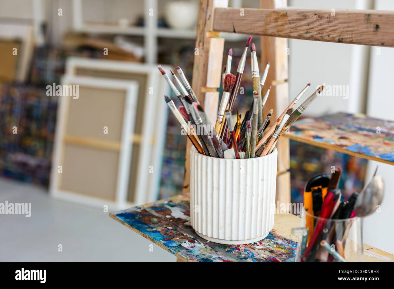 Pinceaux en vase blanc sur chevalet en studio d'art. Banque D'Images