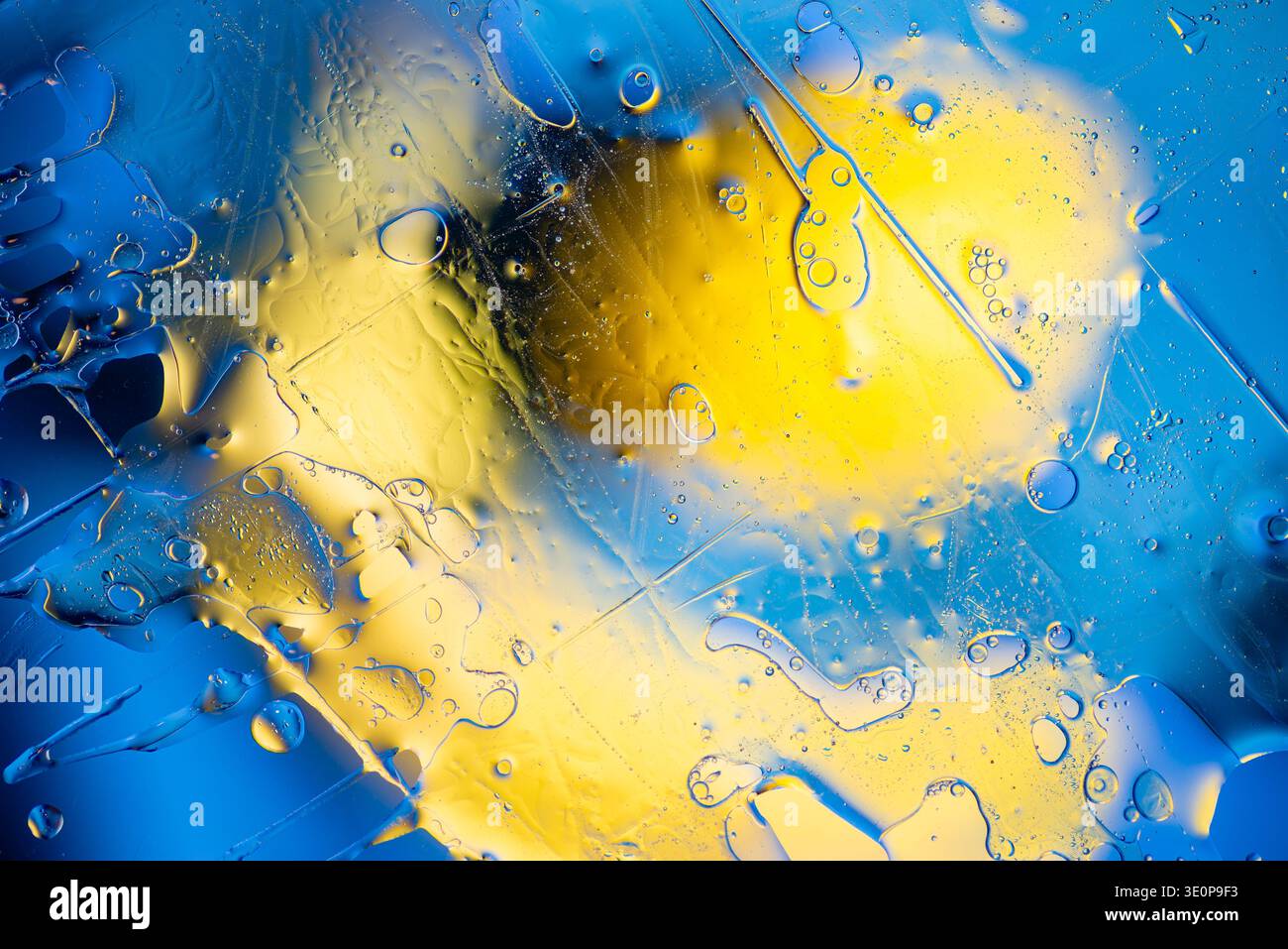 Plan macro artistique de liquides bleus et jaunes tourbillonnants avec bulles d'air et effet bokeh doux créant une sensation d'énergie et de mouvement fluide. Banque D'Images