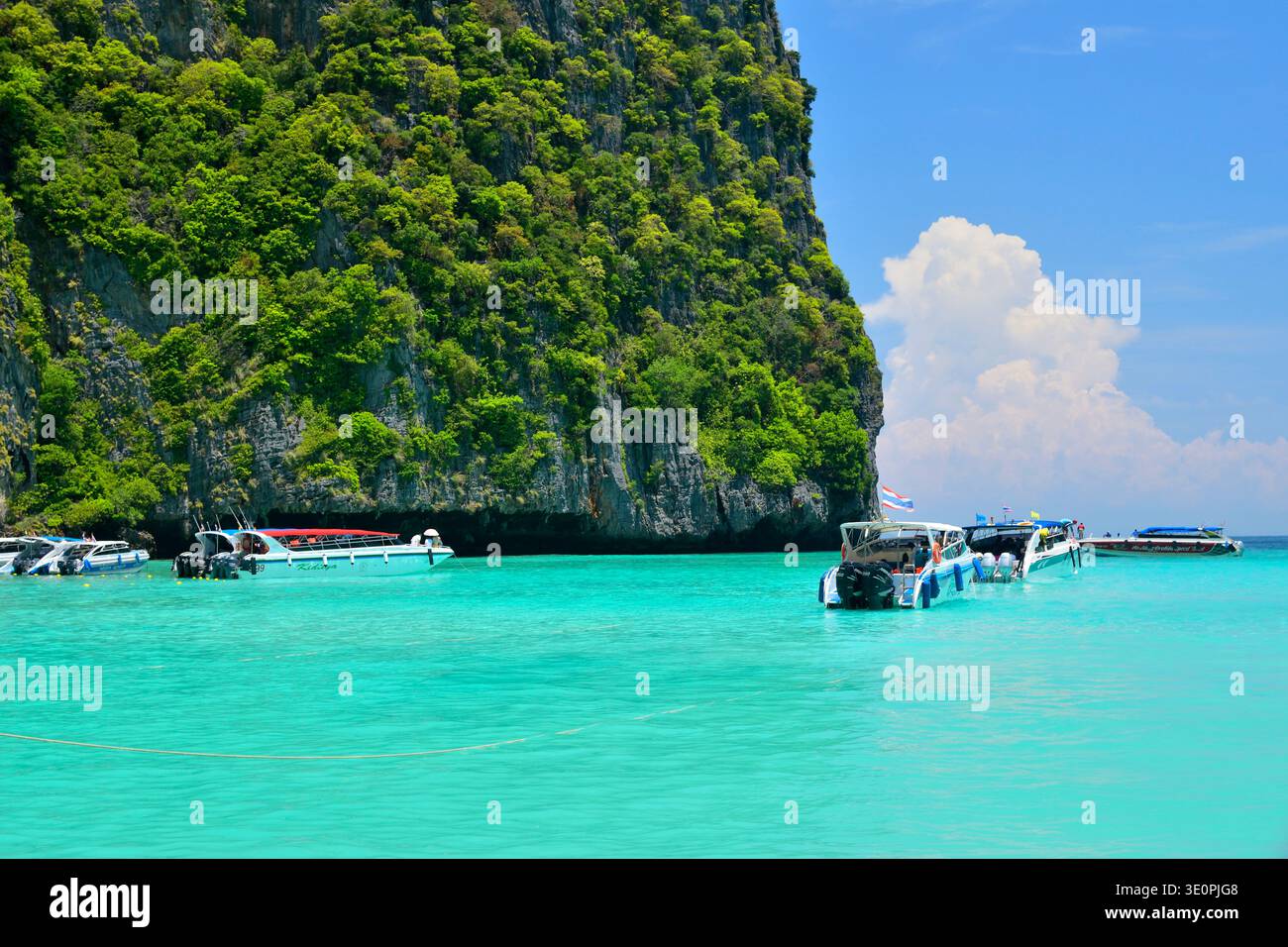 Bateaux à longue queue et touristes entrant dans les eaux turquoises de la baie de Maya sur Ko Phi Phi Leh dans la province de Krabi, en Thaïlande, entourés de calcaires spectaculaires Banque D'Images