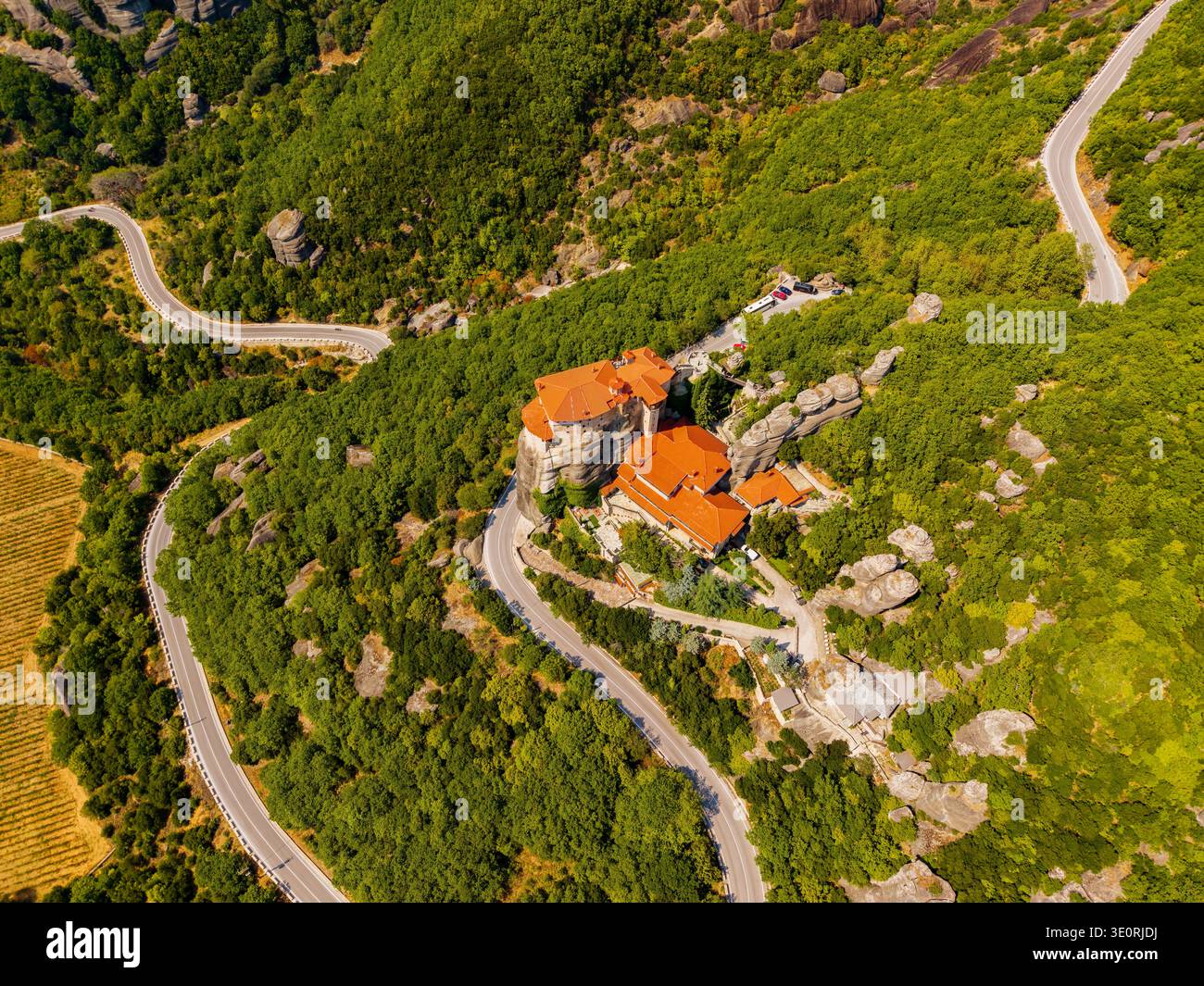 Vue aérienne du monastère perché sur un éperon rocheux, entouré de forêts verdoyantes et de routes sinueuses, Météores, Trikala, Grèce. Banque D'Images