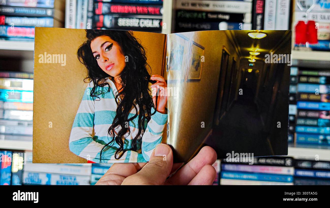 Main tenant un livret de CD ouvert pour l'album Back to Black d'Amy Winehouse avec portrait et couloir intérieur de l'hôtel Banque D'Images