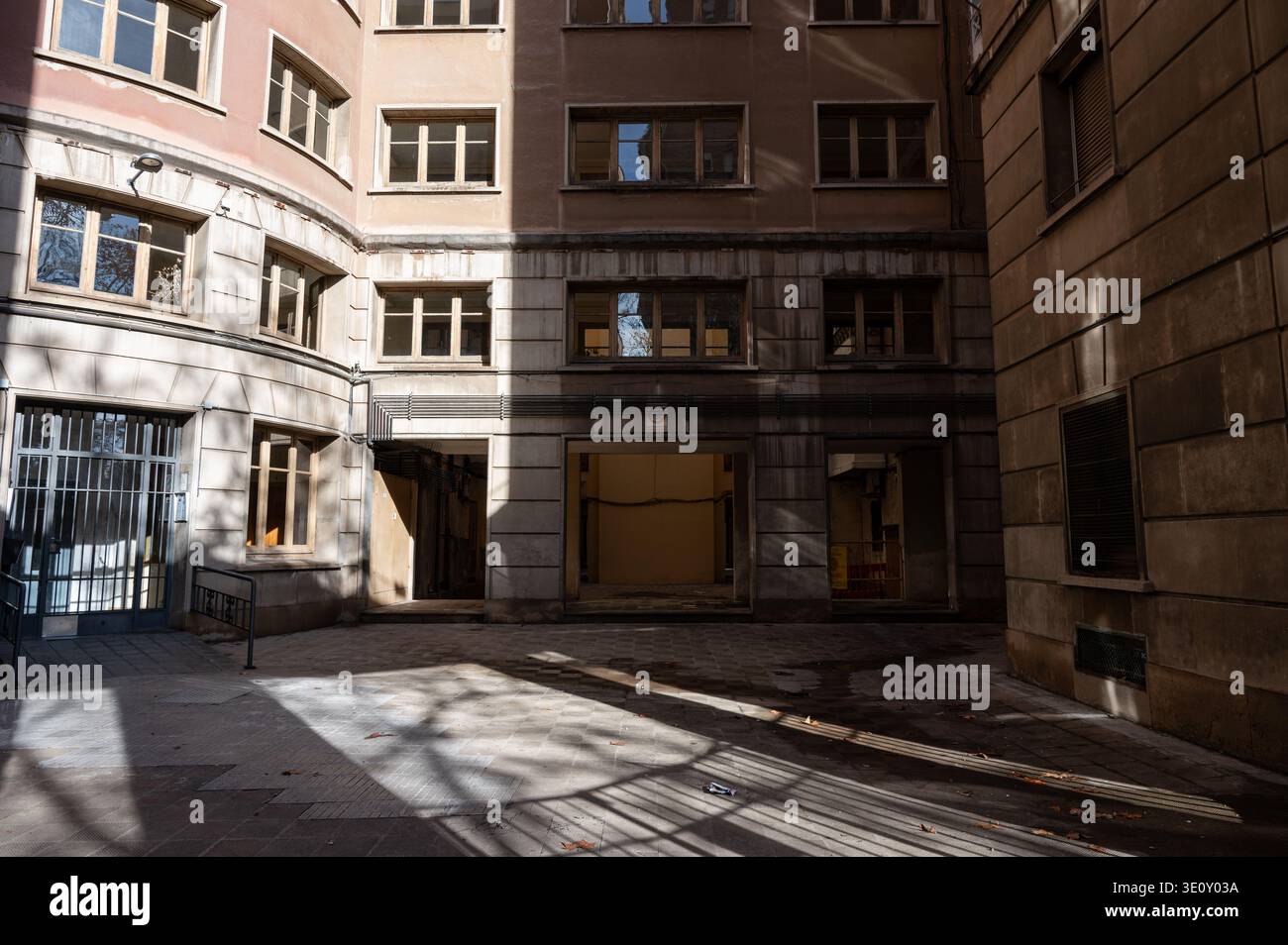 Cour intérieure et entrée d'un complexe d'appartements résidentiels du milieu du siècle à Barcelone présentant une architecture fonctionnaliste et pavée commune Banque D'Images