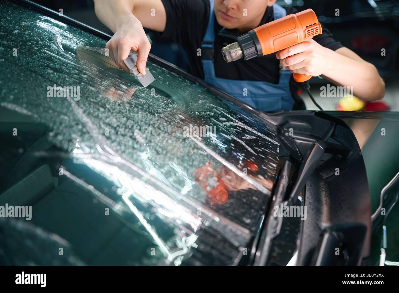 Détendeur pour automobile éliminant l'humidité et les bulles d'air d'un film de pare-brise Banque D'Images