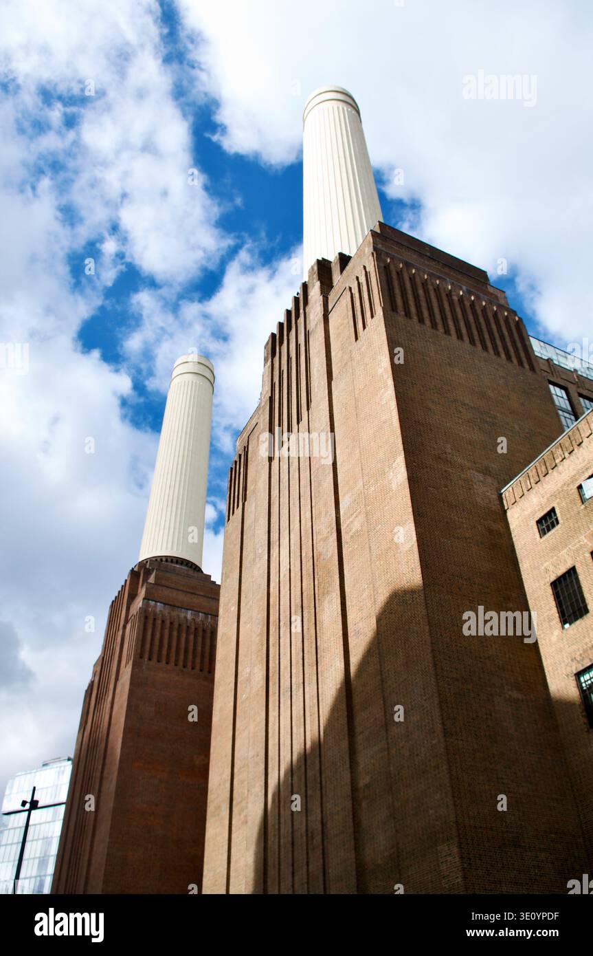 La façade imposante en briques de la centrale électrique de Battersea et ses cheminées blanches jumelées s'élèvent contre un ciel bleu vif, mettant en valeur l'architecture industrielle, urbaine Banque D'Images