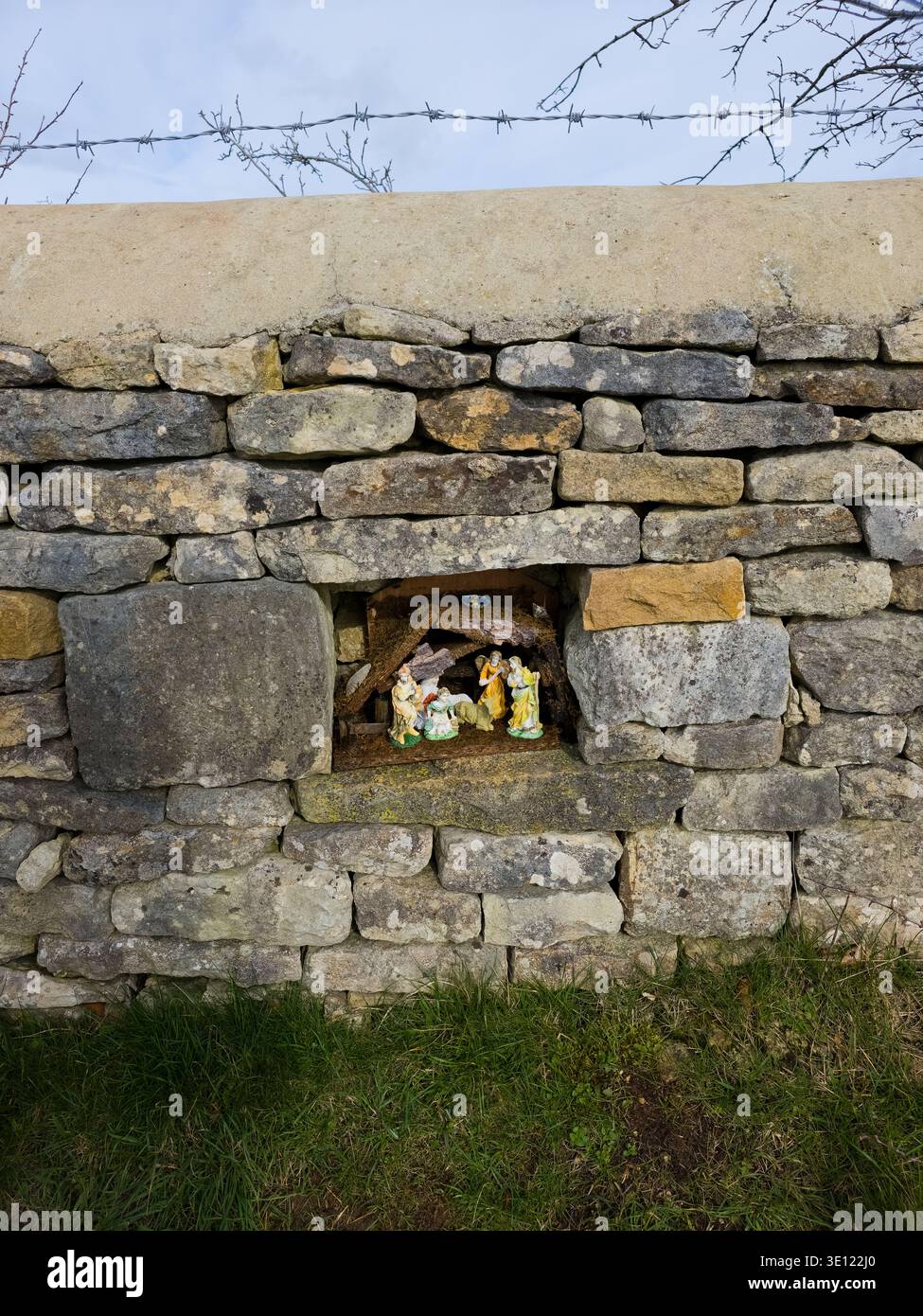 Roadside Shrine Grotto dans Cotswold Stone Wall avec figurines religieuses, région de Stroud, Gloucestershire, Angleterre - Image de stock capturée avec un smartphone