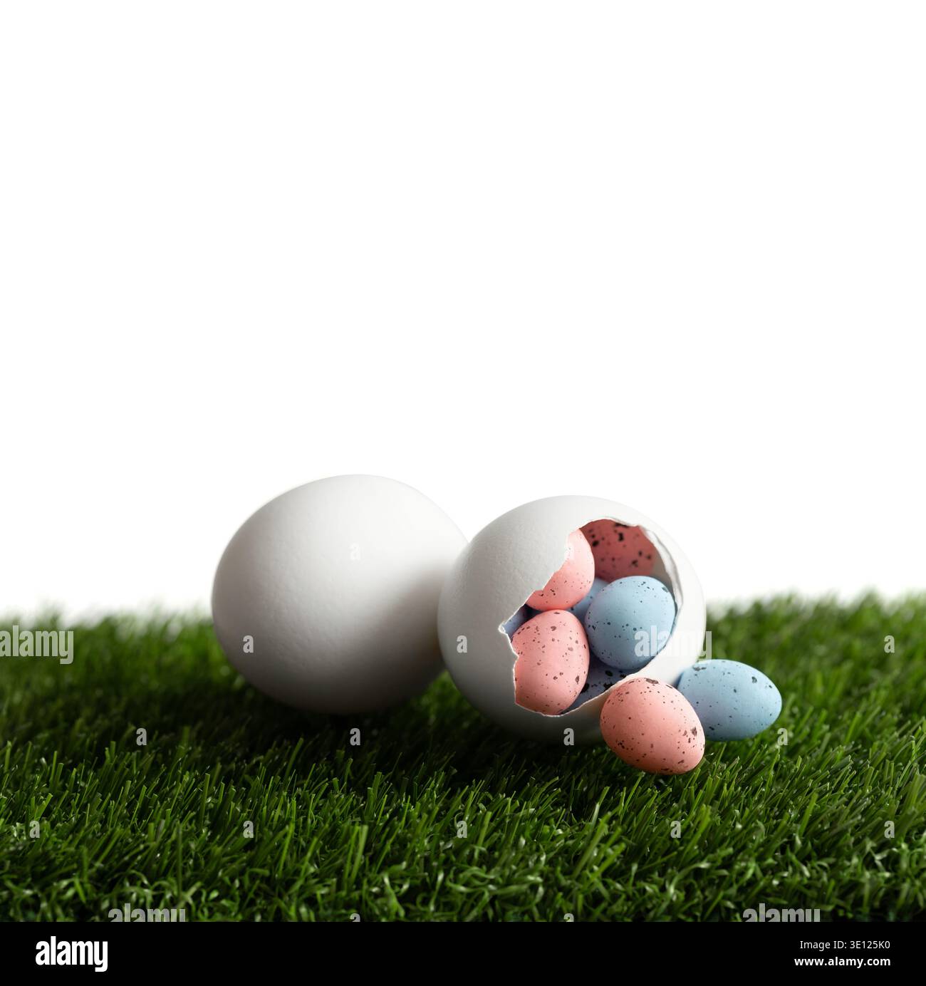Composition de Pâques avec de petits oeufs peints dans un oeuf de poule blanc éclos sur une pelouse verte. Décor festif de Pâques isolé sur un fond blanc. Copier s Banque D'Images