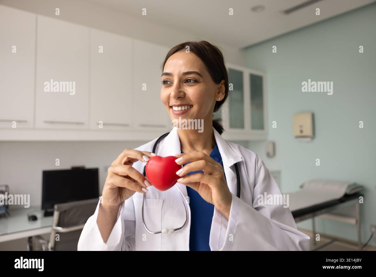 Médecin moyen-oriental en uniforme tenant le modèle de coeur rouge en clinique Banque D'Images