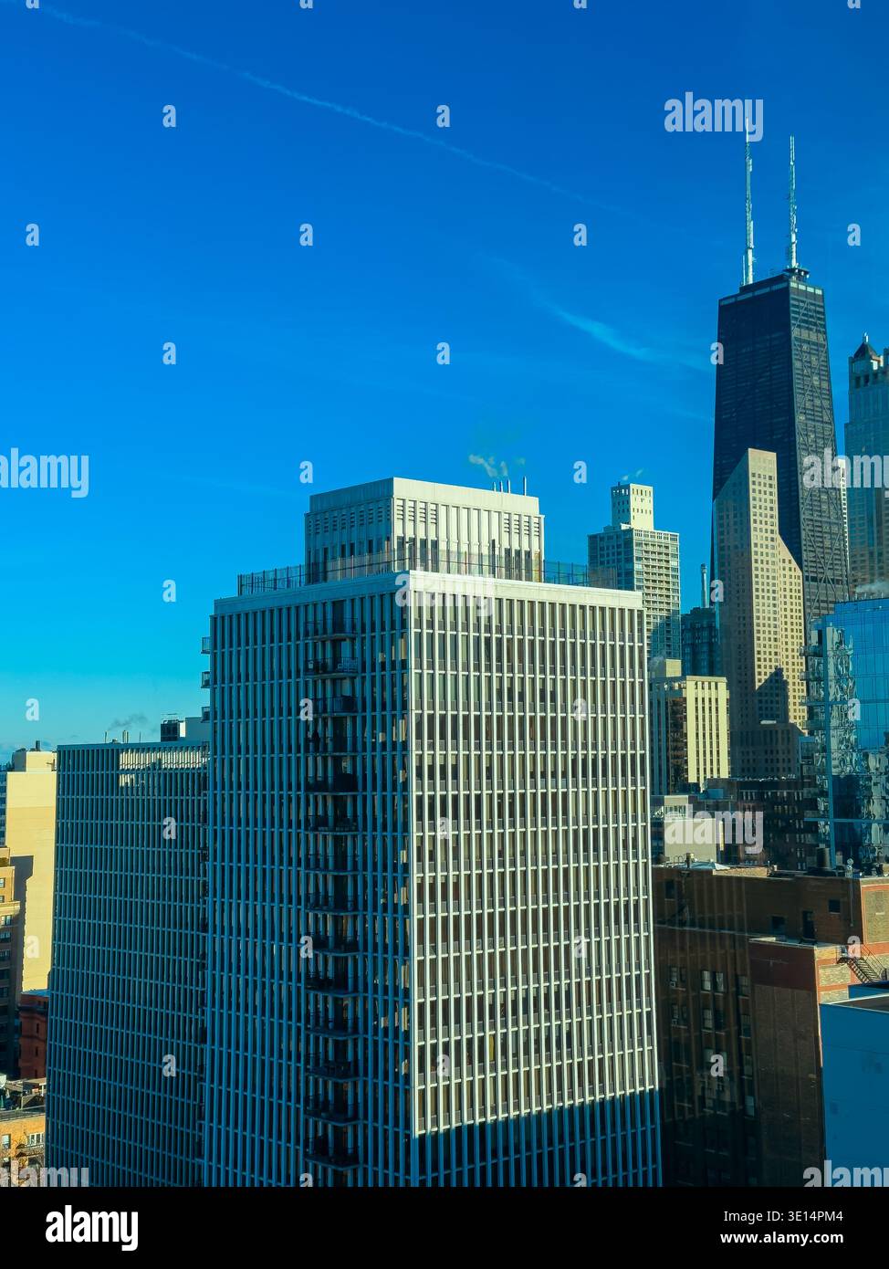 De grands bâtiments s'élèvent contre un ciel bleu clair dans une zone urbaine. La scène montre une architecture moderne et une atmosphère lumineuse de jour. Banque D'Images
