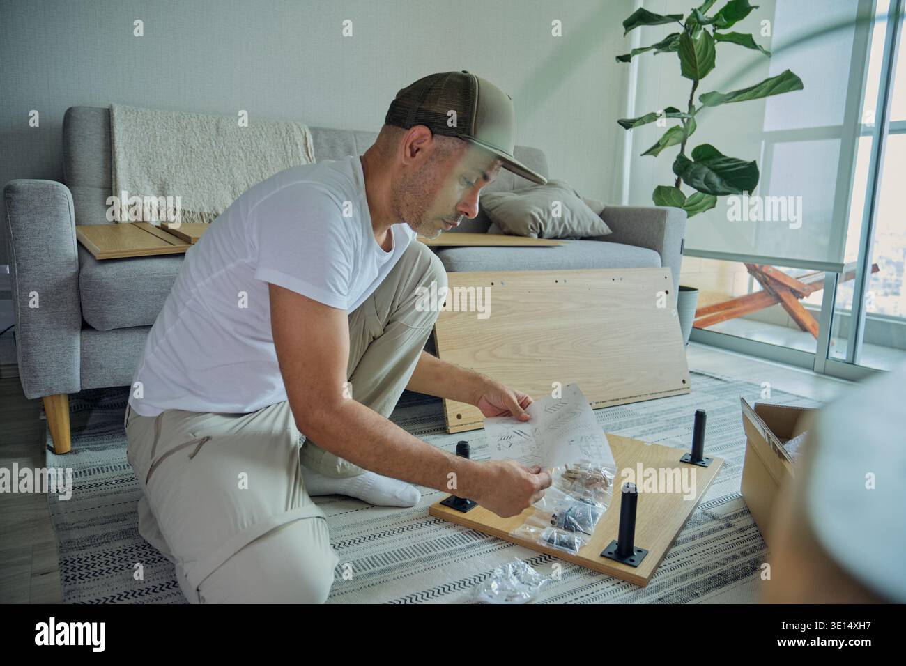 Homme examinant les instructions pour la construction de meubles en bois à la maison Banque D'Images