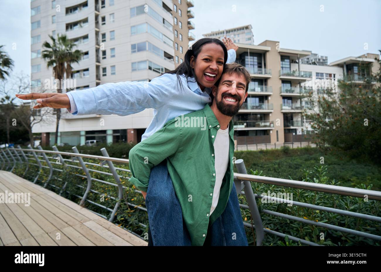 Couple interracial piggyback et souriant à la caméra à l'extérieur Banque D'Images