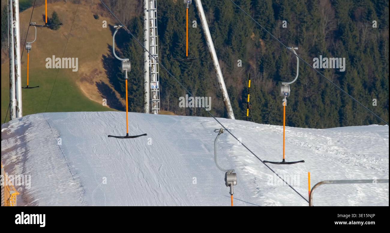 Remontée mécanique en service sur une montagne enneigée avec un ciel clair et de l'herbe verte en arrière-plan pendant l'hiver Banque D'Images