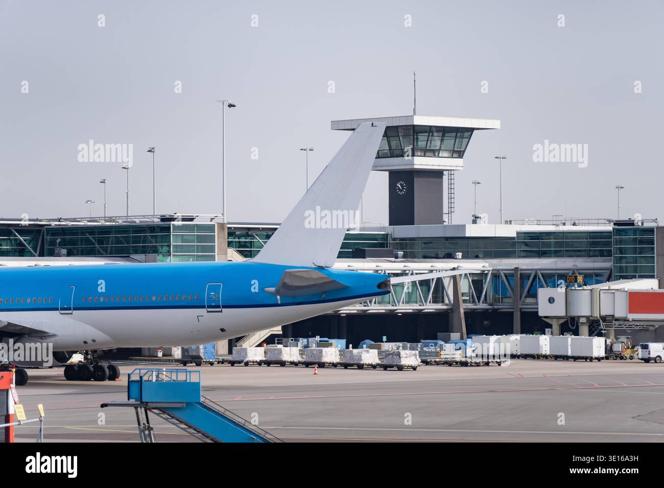 Queue d'avion bleue et blanche près du terminal de l'aéroport et de la tour de contrôle, mettant en évidence la logistique de l'aviation commerciale, les opérations de porte et la gestion de la flotte Banque D'Images