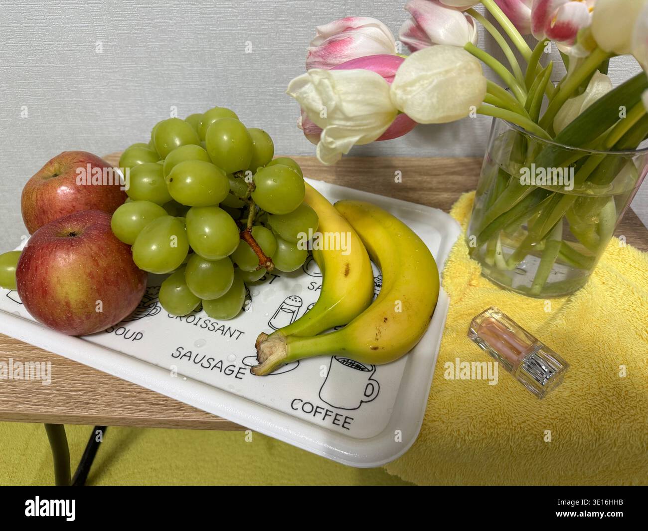 Nature morte avec fruits frais, bouquet de bananes, raisins verts, pomme rouge et fleurs de tulipes roses Banque D'Images
