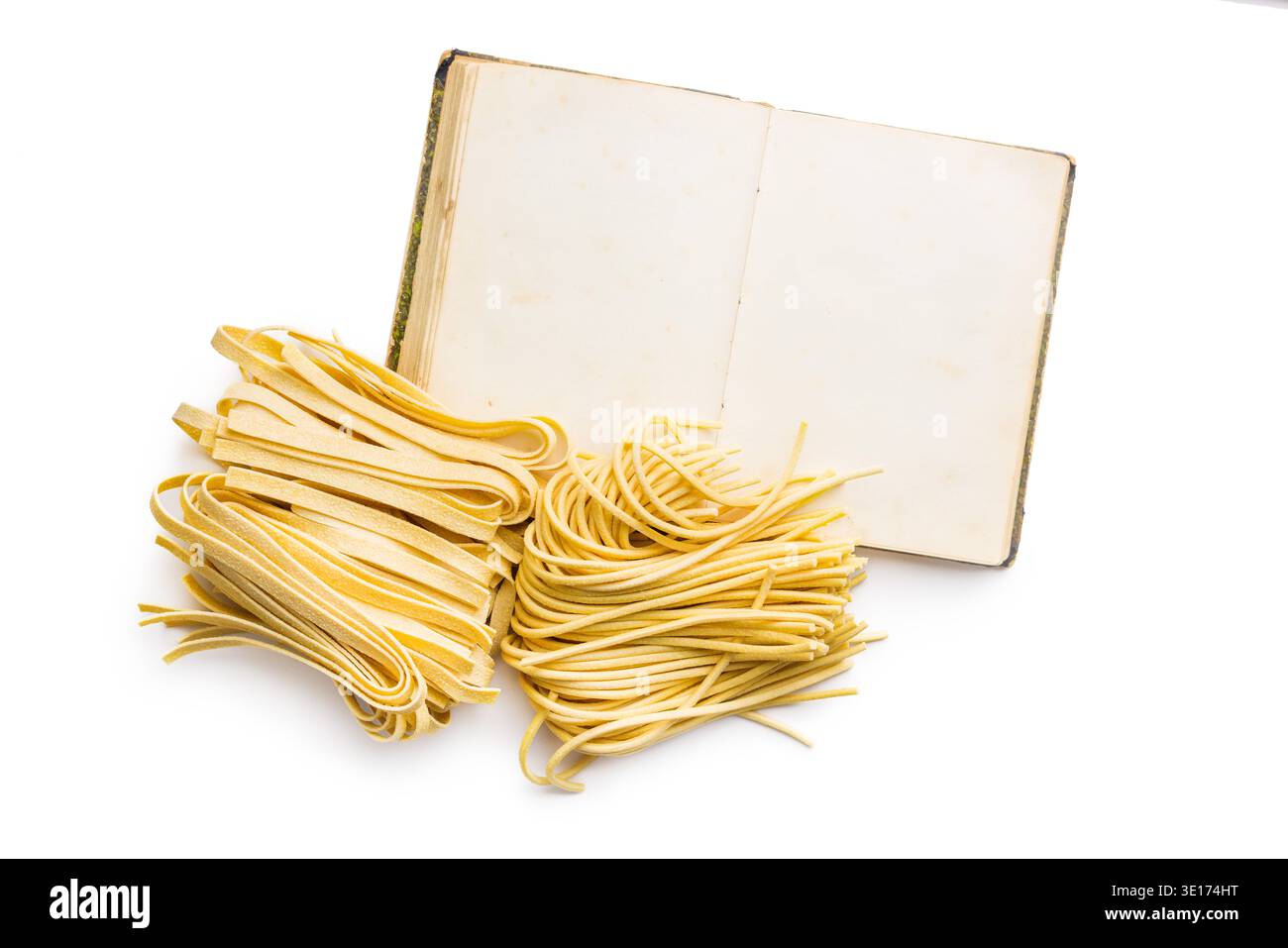 Livre de recettes. Des brins de fettuccine et de bigoli reposent sur une surface blanche, paraissant doux et frais. Ce type de pâtes est souvent utilisé dans divers plats. Banque D'Images
