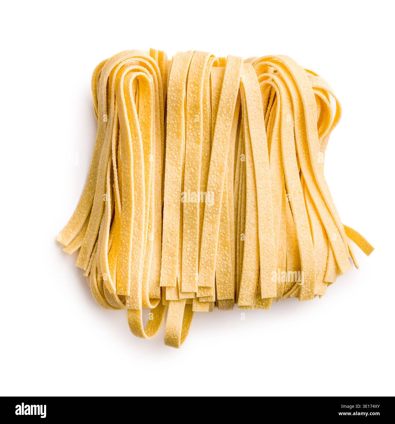Les brins de pâtes fettuccine reposent sur une surface blanche, paraissant doux et frais. Ce type de pâtes est souvent utilisé dans divers plats. Banque D'Images
